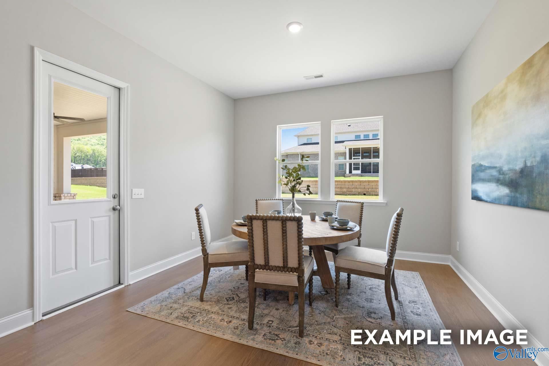 Elegant dining room with round wood table, tufted chairs, French door to porch in 5-bedroom The Haven E home, Owens Cross Roads, AL