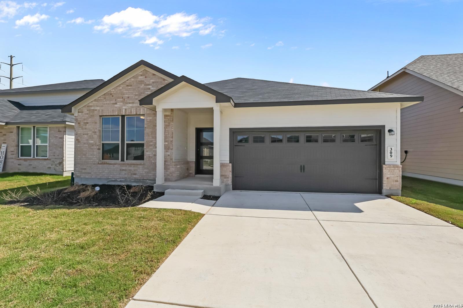 Modern tan brick single-story home with 2-car garage, covered entry porch, and lush front yard in Hannah Heights, Seguin, Texas - The Daphne H by Davidson Homes