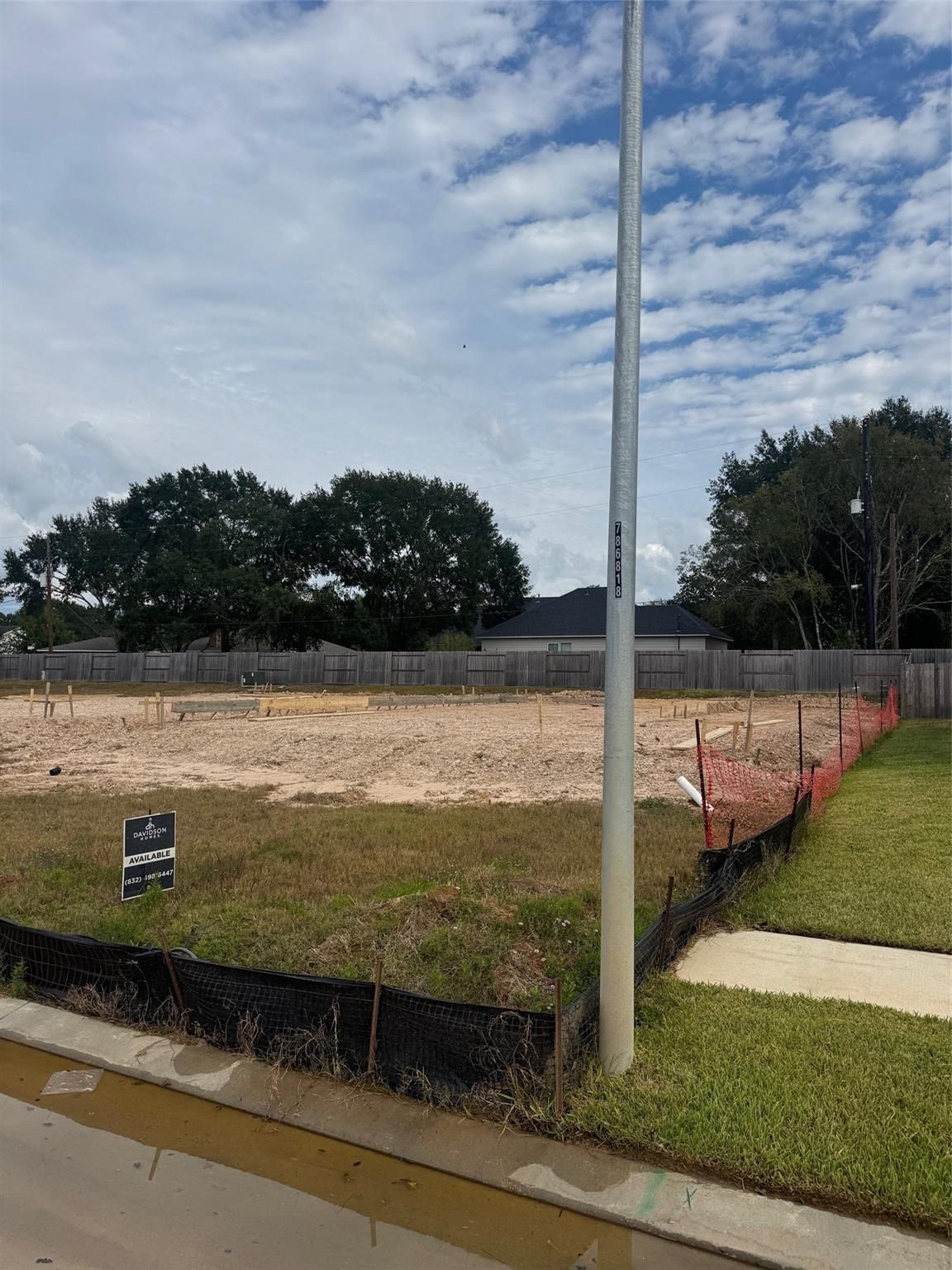 Cleared construction lot with fencing, for-sale sign, and oak trees for Davidson Homes Sabine F in Windmill Estates, Magnolia, Texas