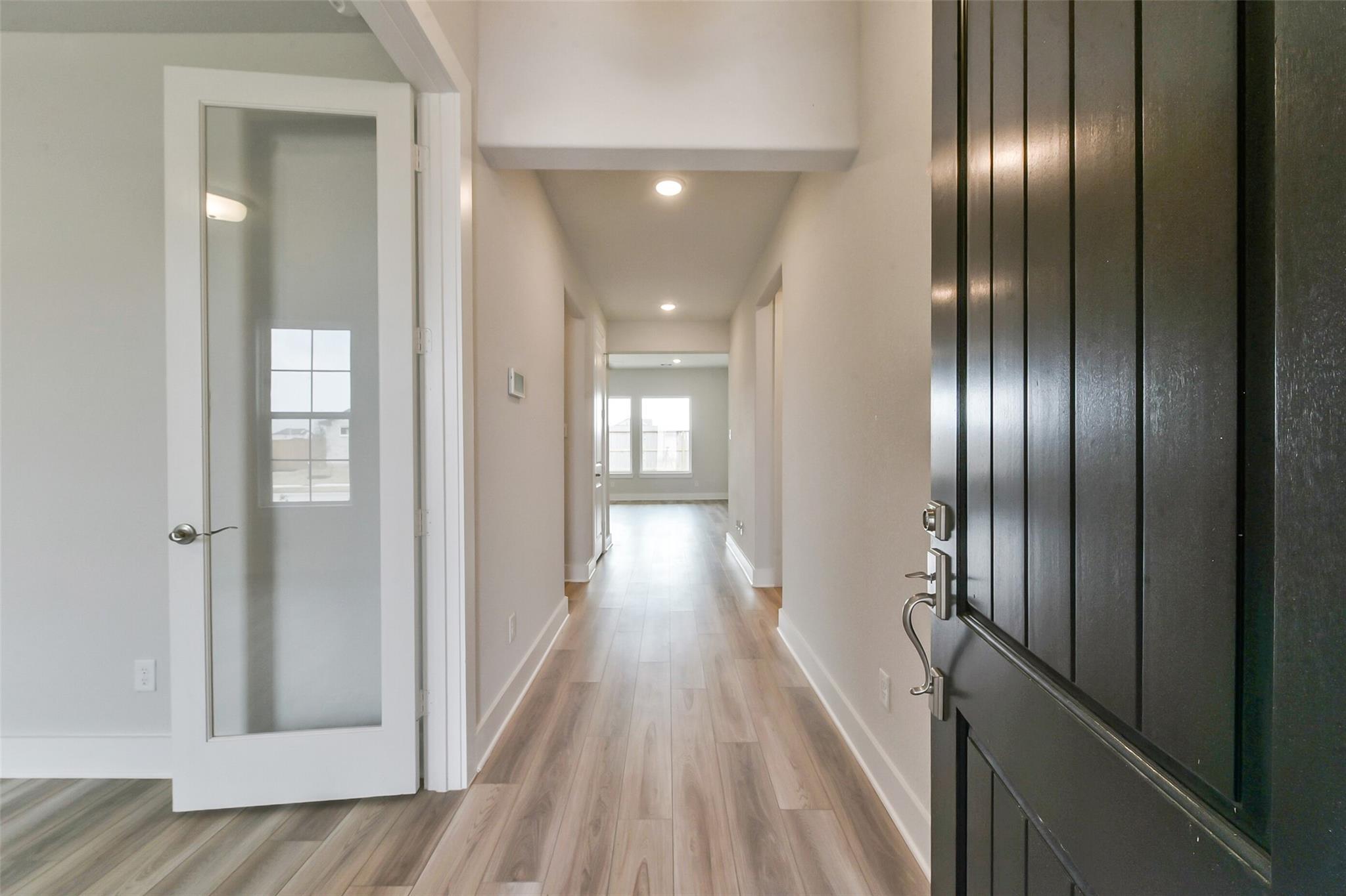 Bright entry hallway with light wood floors, frosted glass doors, and recessed lighting in Davidson Homes The Edward A, Lago Mar, Texas City