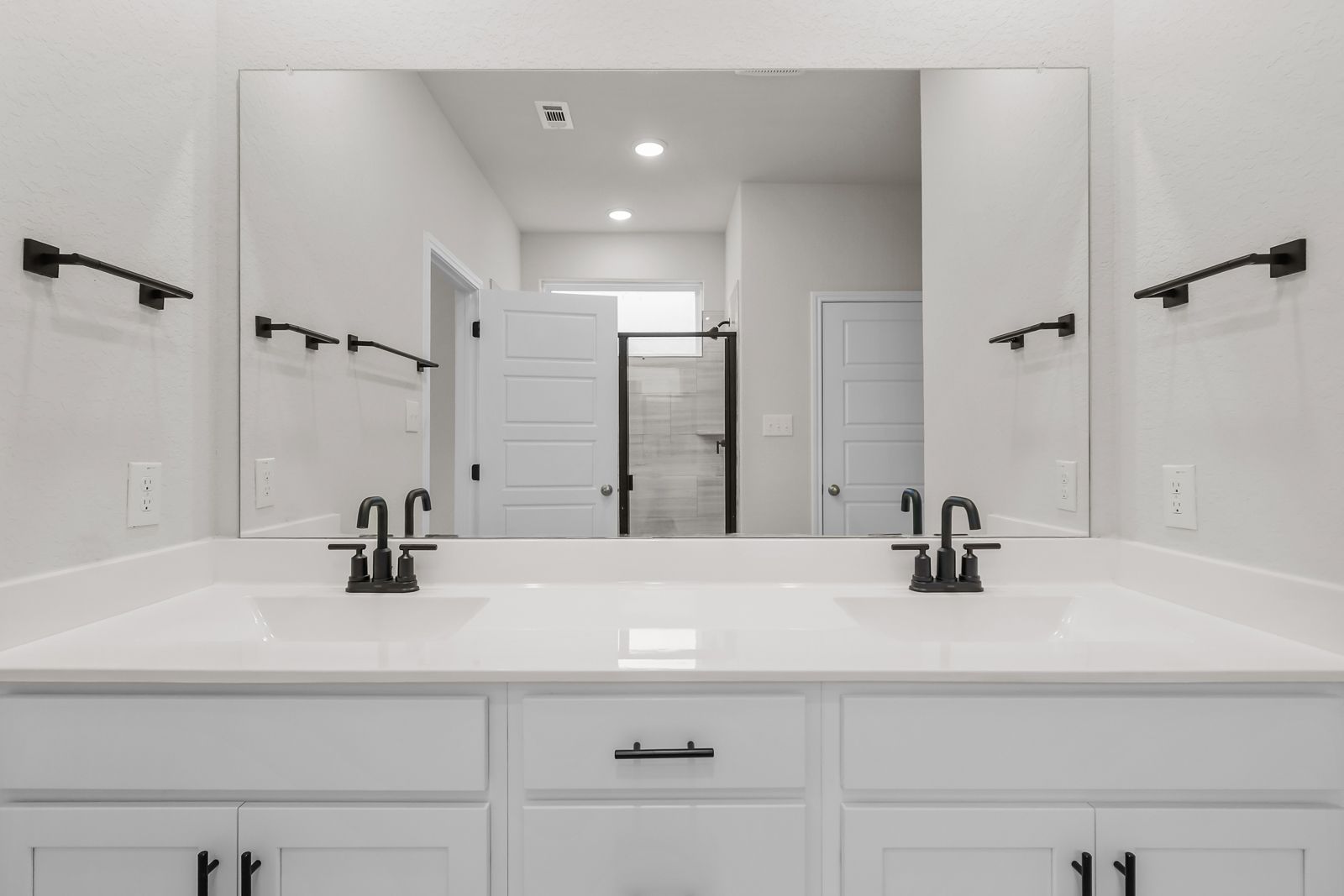 Modern primary bathroom vanity in The Sequoia C featuring dual sinks, matte black fixtures, and white cabinetry.