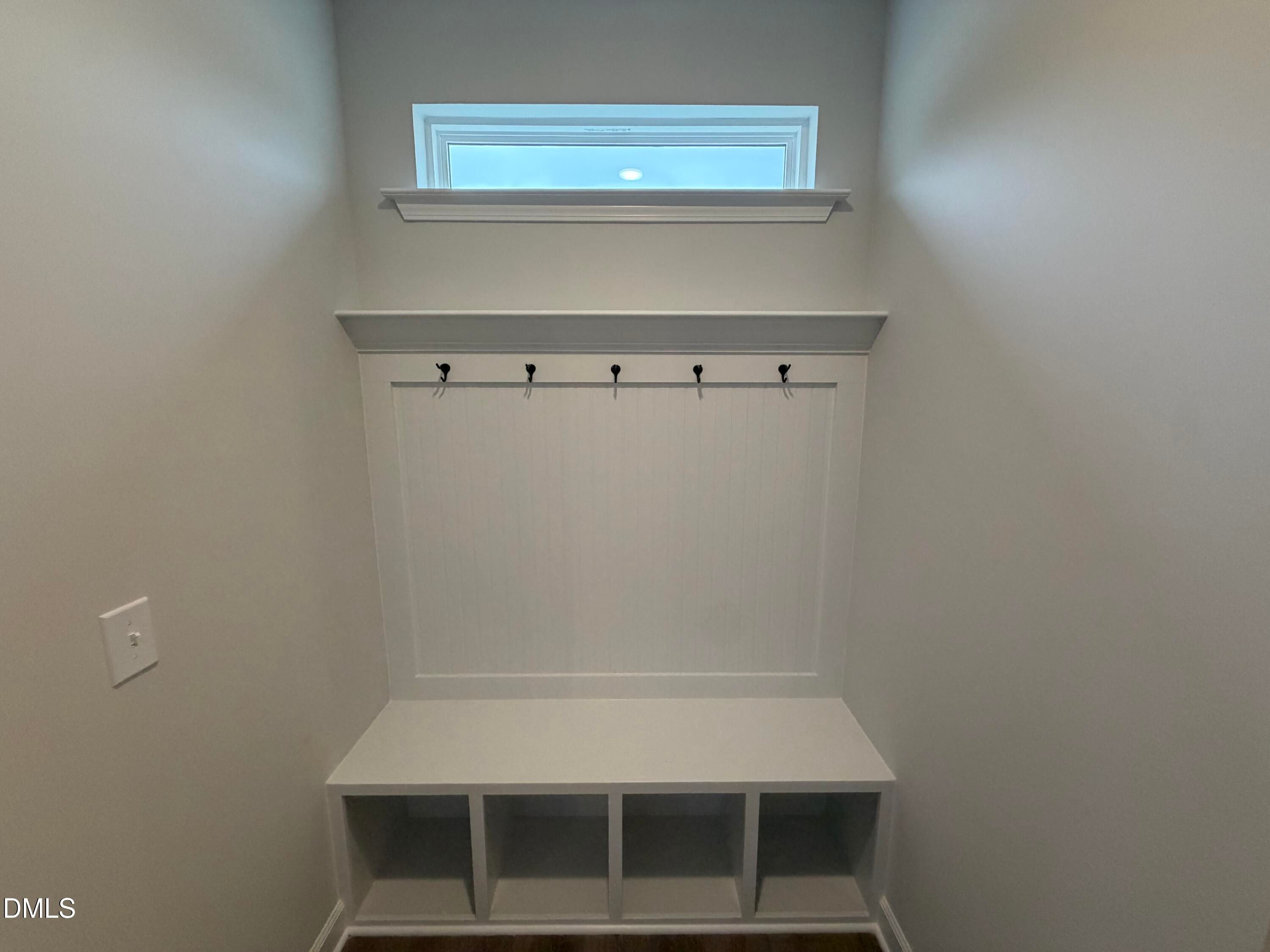White mudroom with built-in bench, cubby storage, coat hooks, and transom window in Davidson Homes The Preston C, Wendell Ridge