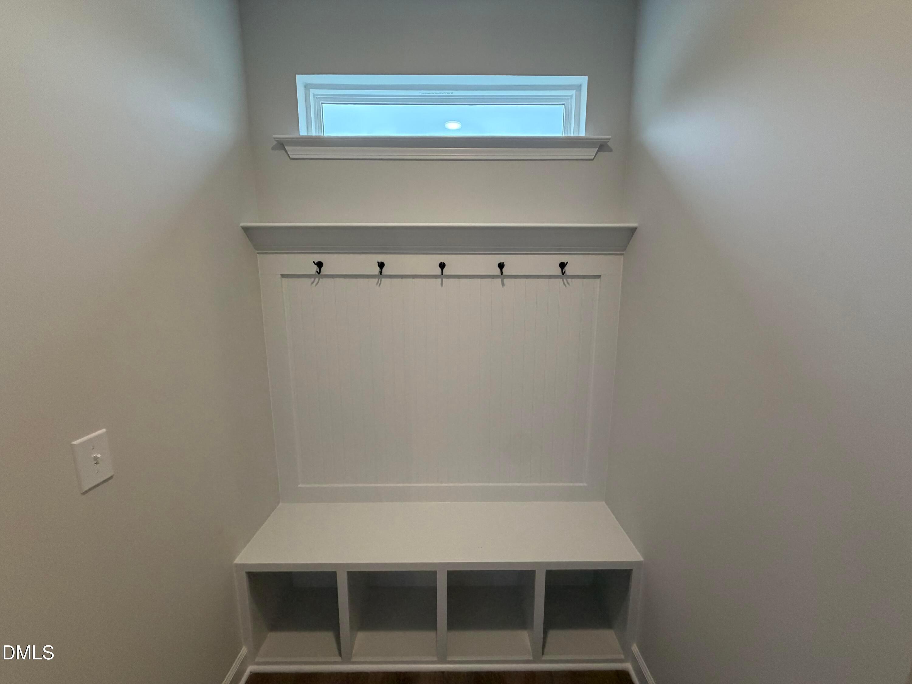 White mudroom with built-in bench, cubby storage, coat hooks, and transom window in Davidson Homes The Preston C, Wendell Ridge