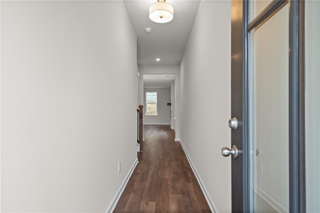 Elegant hallway with hardwood floors, white walls, and glass door in The Marion B, Davidson Homes, Kennesaw, Georgia
