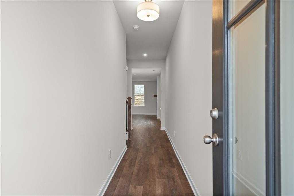Elegant hallway with hardwood floors, white walls, and glass door in The Marion B, Davidson Homes, Kennesaw, Georgia