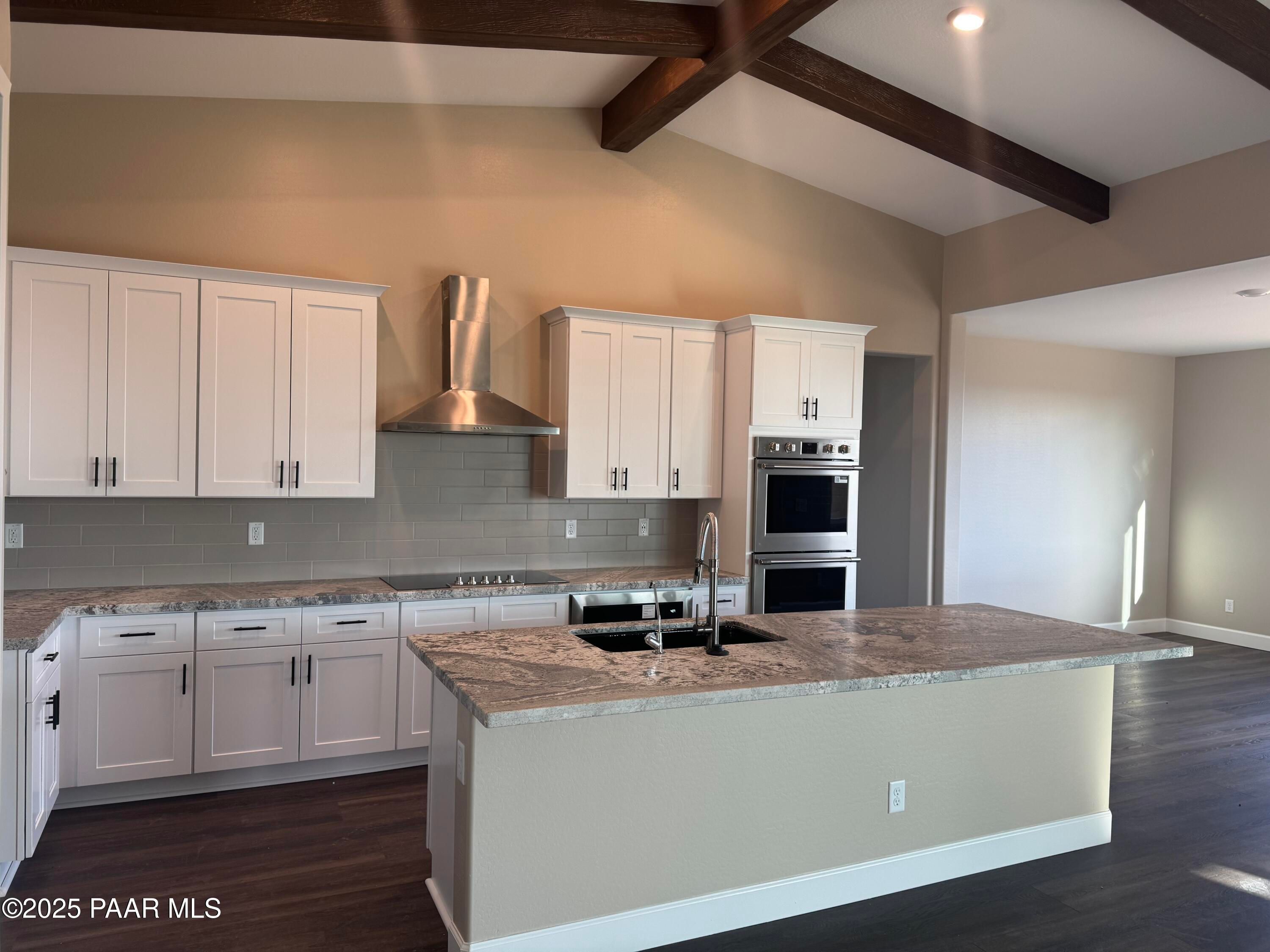 Modern white shaker kitchen with granite island, stainless double ovens, subway tile backsplash in The Sunrise A, Prescott Valley, AZ