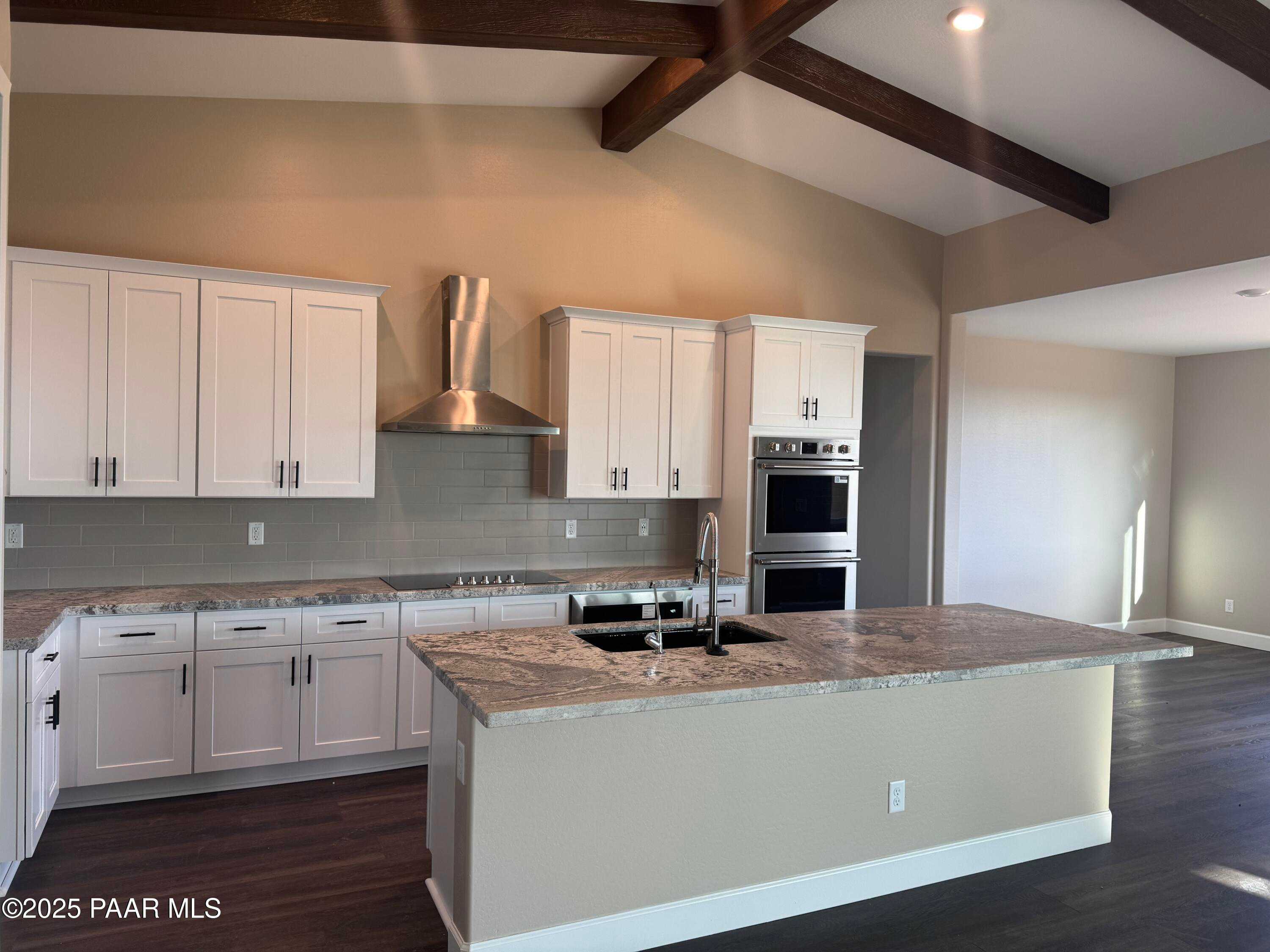 Modern white shaker kitchen with granite island, stainless double ovens, subway tile backsplash in The Sunrise A, Prescott Valley, AZ