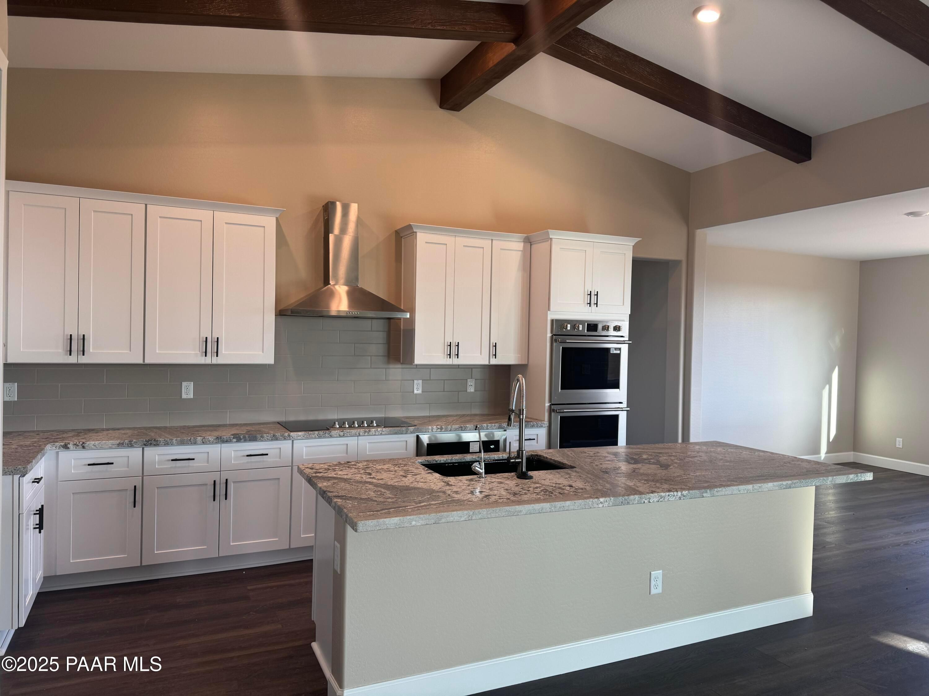 Modern white shaker kitchen with granite island, stainless double ovens, subway tile backsplash in The Sunrise A, Prescott Valley, AZ