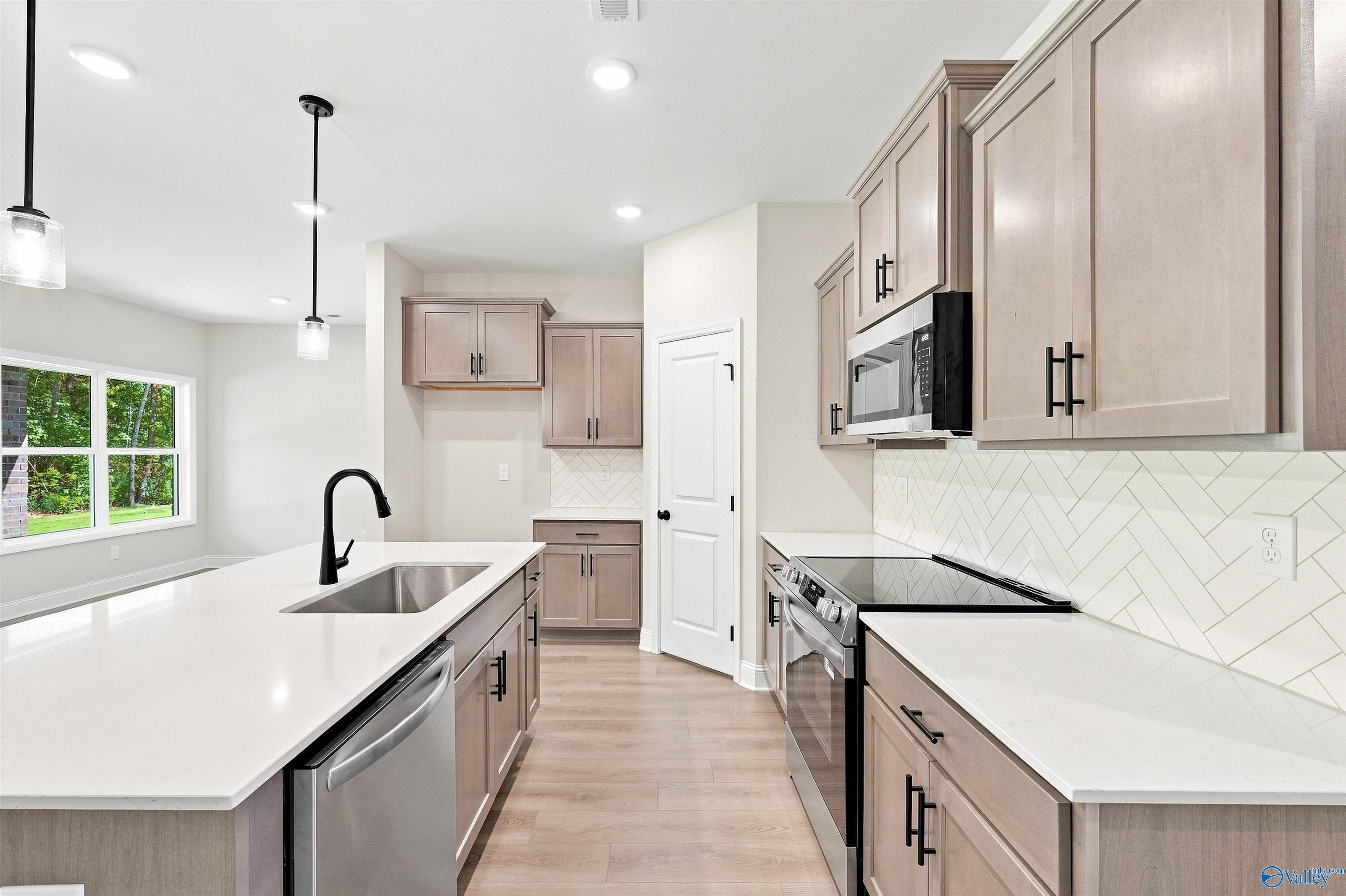 Modern kitchen with white quartz countertops and herringbone backsplash in The Daphne floor plan, Spragins Cove, Huntsville.