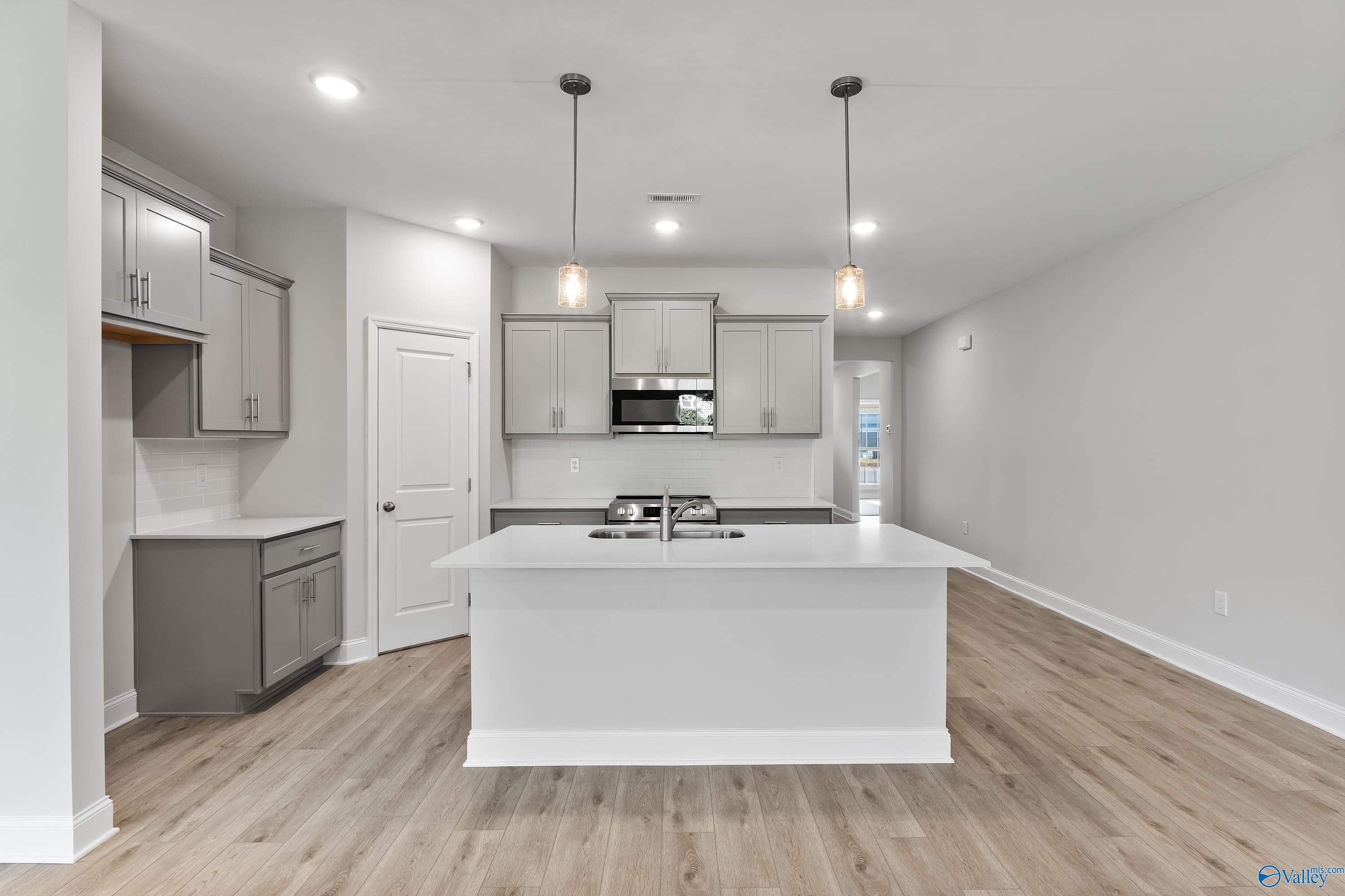 Bright open-concept kitchen with white shaker cabinets, large center island sink, stainless appliances in Davidson Homes The Daphne C, Huntsville, Alabama