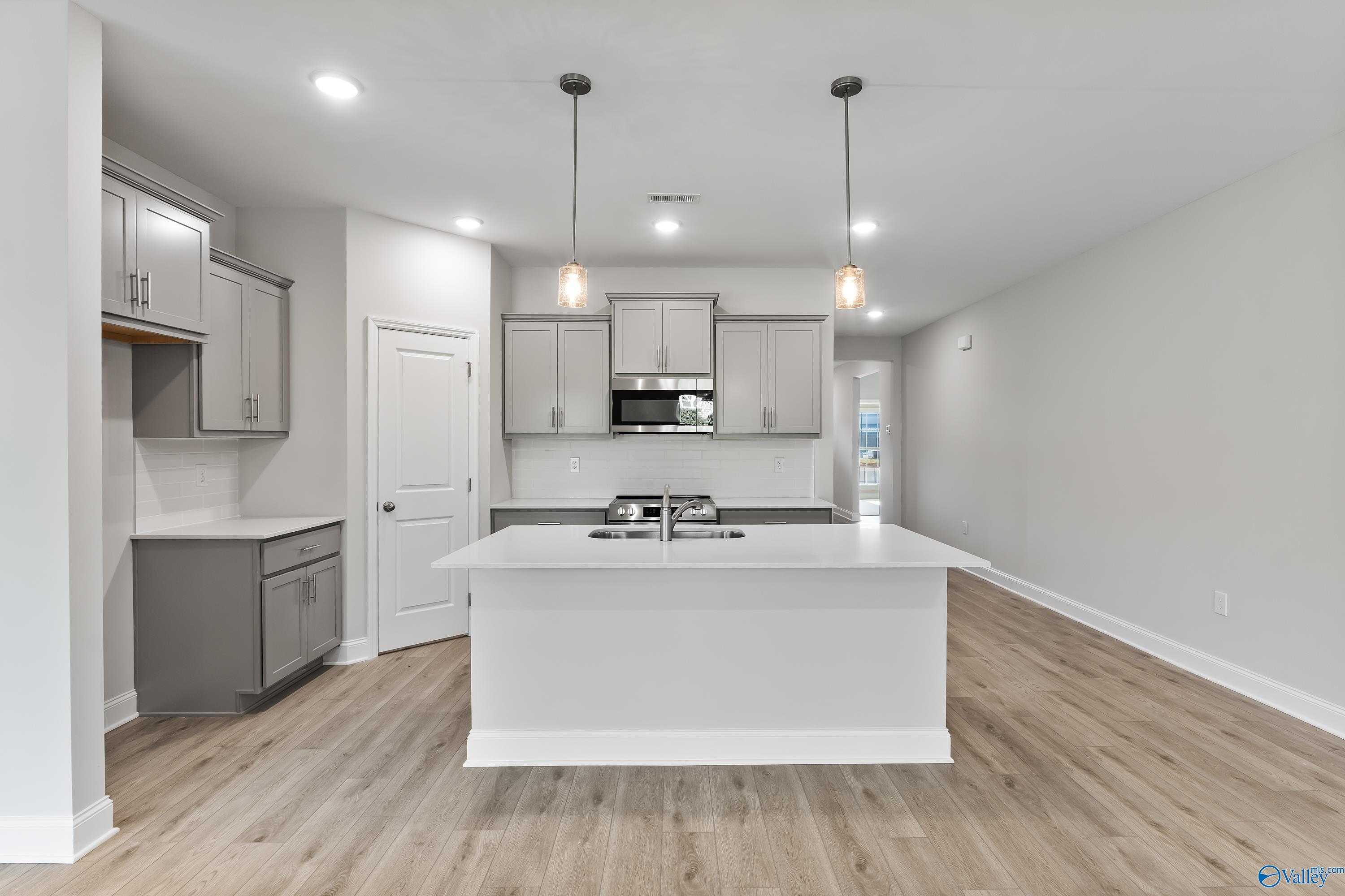 Bright open-concept kitchen with white shaker cabinets, large center island sink, stainless appliances in Davidson Homes The Daphne C, Huntsville, Alabama