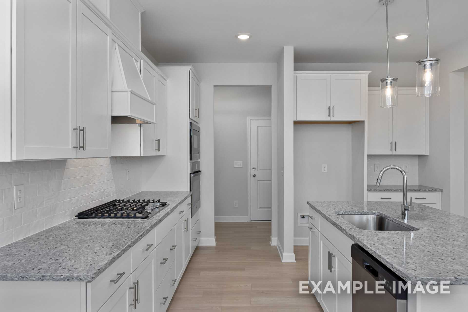 Spacious kitchen in The Gavin C plan featuring white shaker cabinets, gray granite island with sink, stainless steel appliances