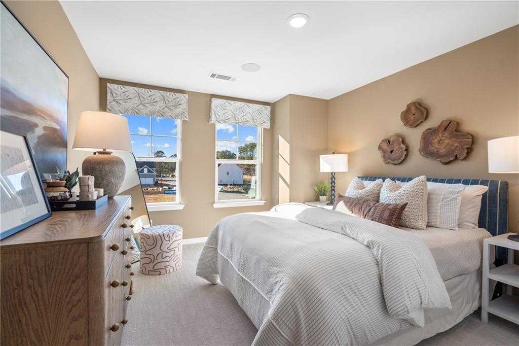 Elegant master bedroom with plush white bedding, wooden dresser, and driftwood wall art in Davidson Homes The Marion C, Winder, GA
