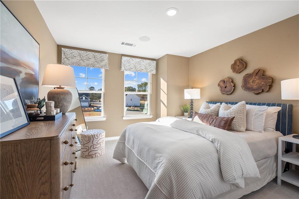 Elegant master bedroom with plush white bedding, driftwood wall art, and sunny windows in Davidson Homes The Marion B, Kennesaw