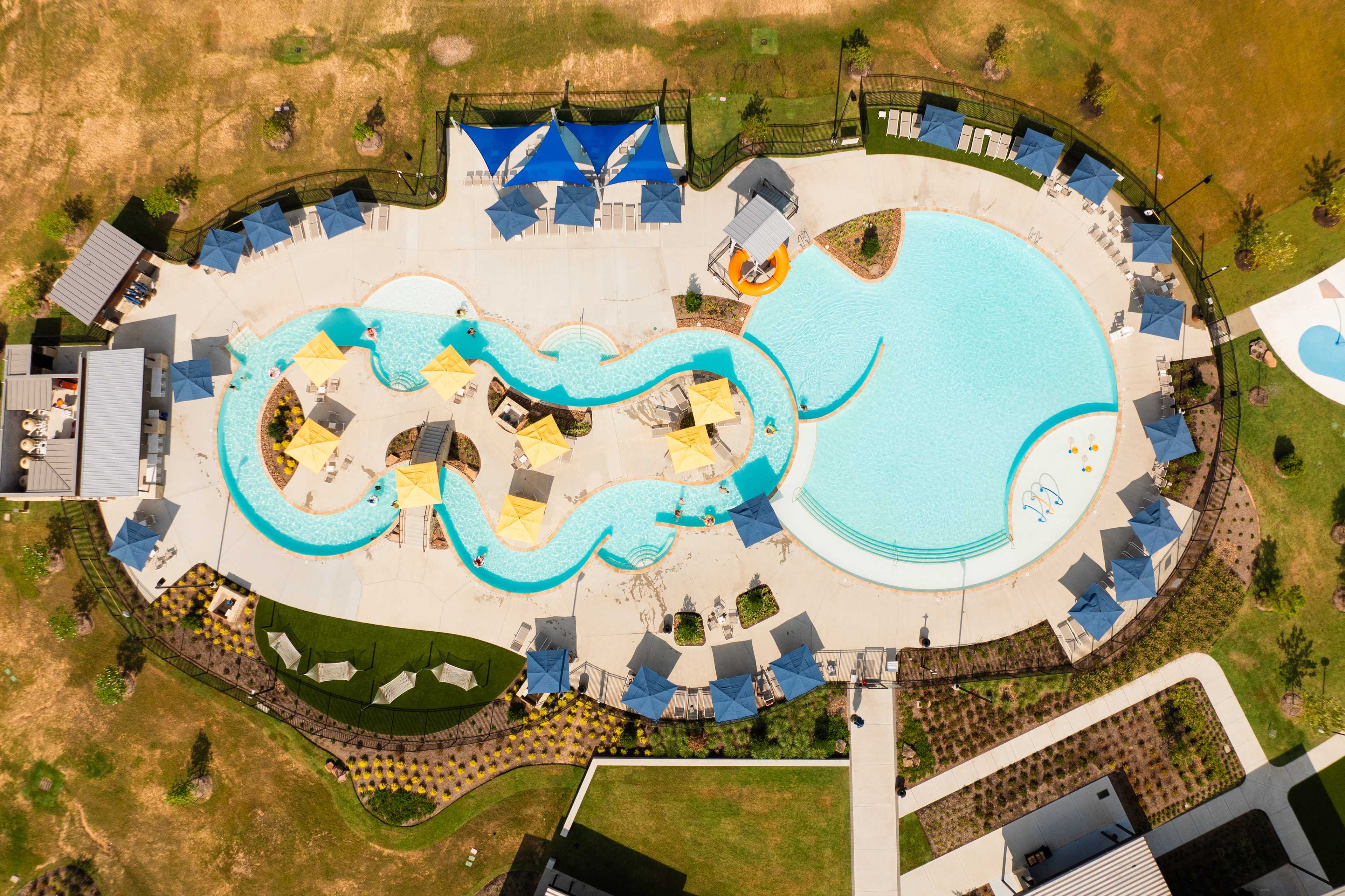 Resort-style lazy river pool at Sunterra in Katy Texas with winding blue waters yellow umbrellas and lounge seating