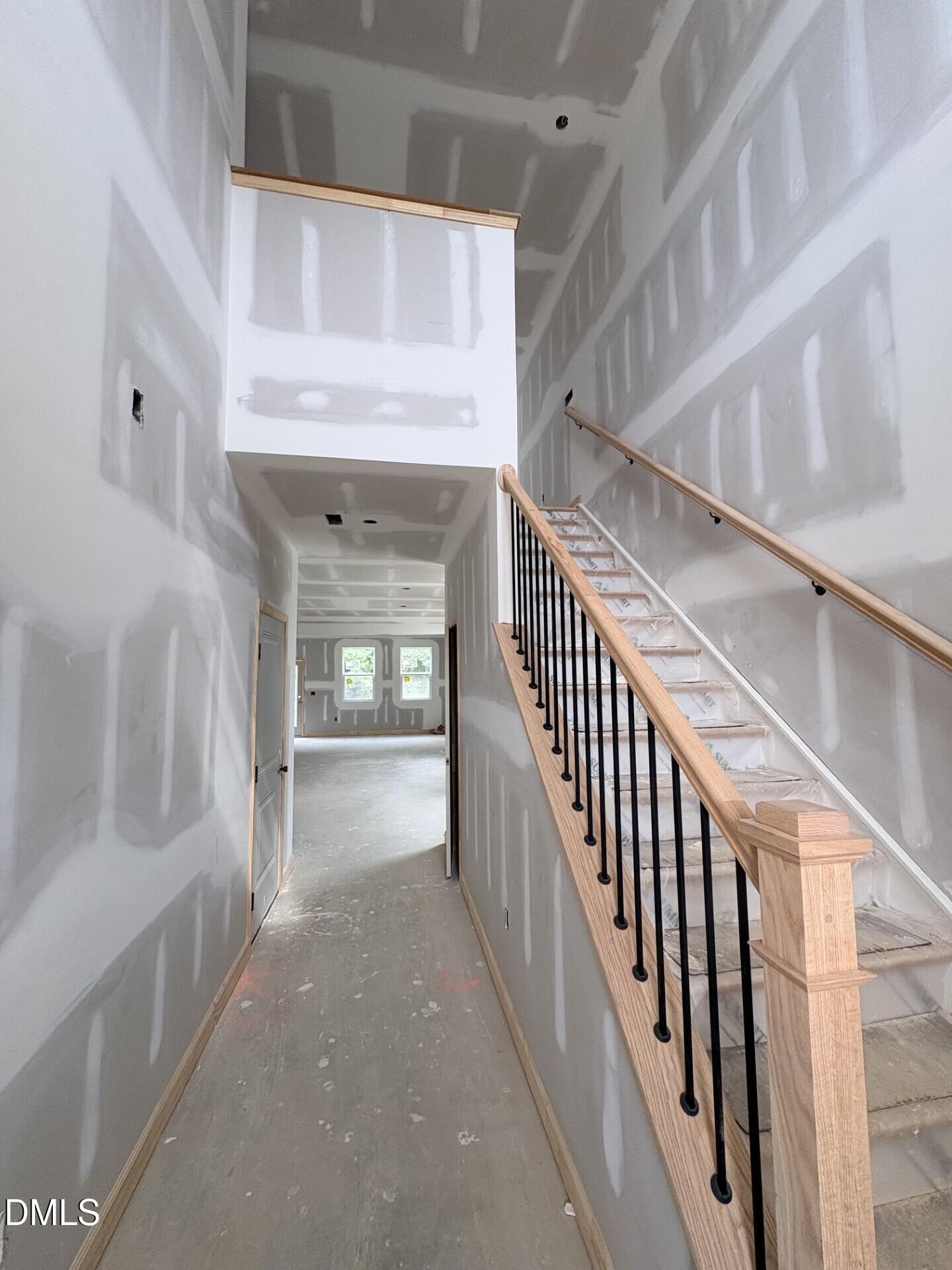 Unfinished interior hallway with wooden staircase and black iron railings in The Adalynn A floor plan, Zebulon, North Carolina.