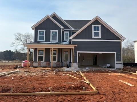 Two-story gray shake siding home with white trim, covered front porch, and open two-car garage in Cedar Farms, Winder, Georgia