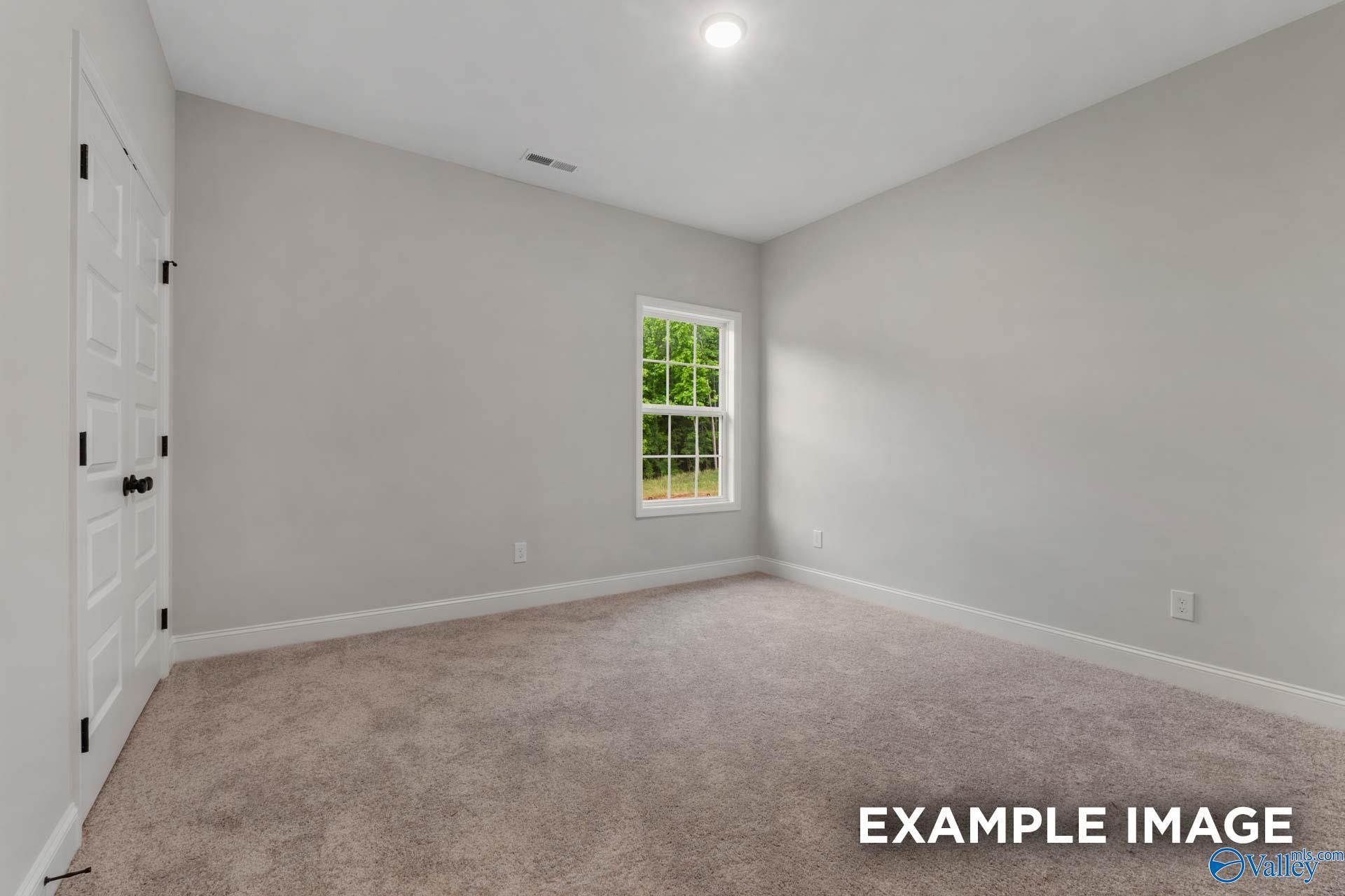 Bright secondary bedroom with light gray walls, beige carpet, and window in Davidson Homes The Finleigh, Meridianville, Alabama