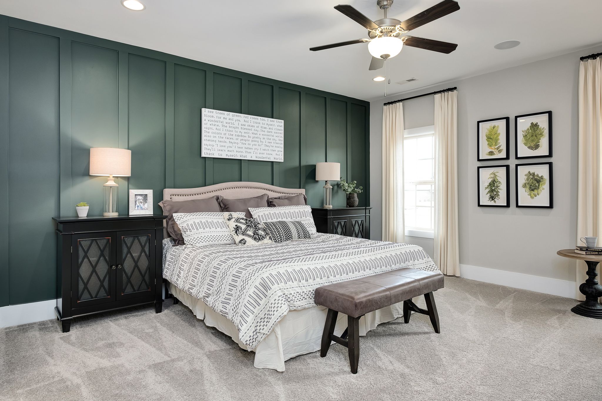 Spacious master bedroom in Chimney Creek, Hampton Cove AL with green accent wall, king bed, ceiling fan, and botanical art by Davidson Homes