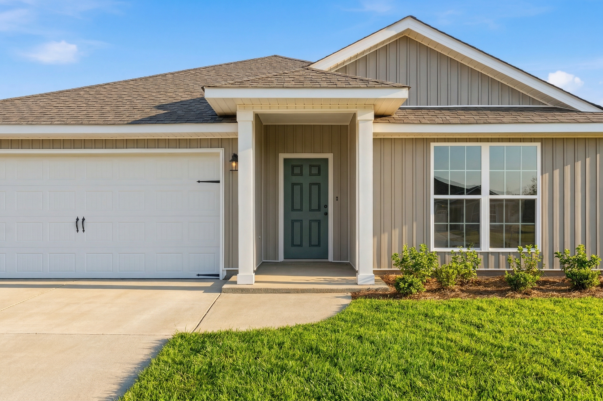 Front elevation of The Daphne V single-story home featuring beige siding, green door, two-car garage, and covered porch in Meridianville AL