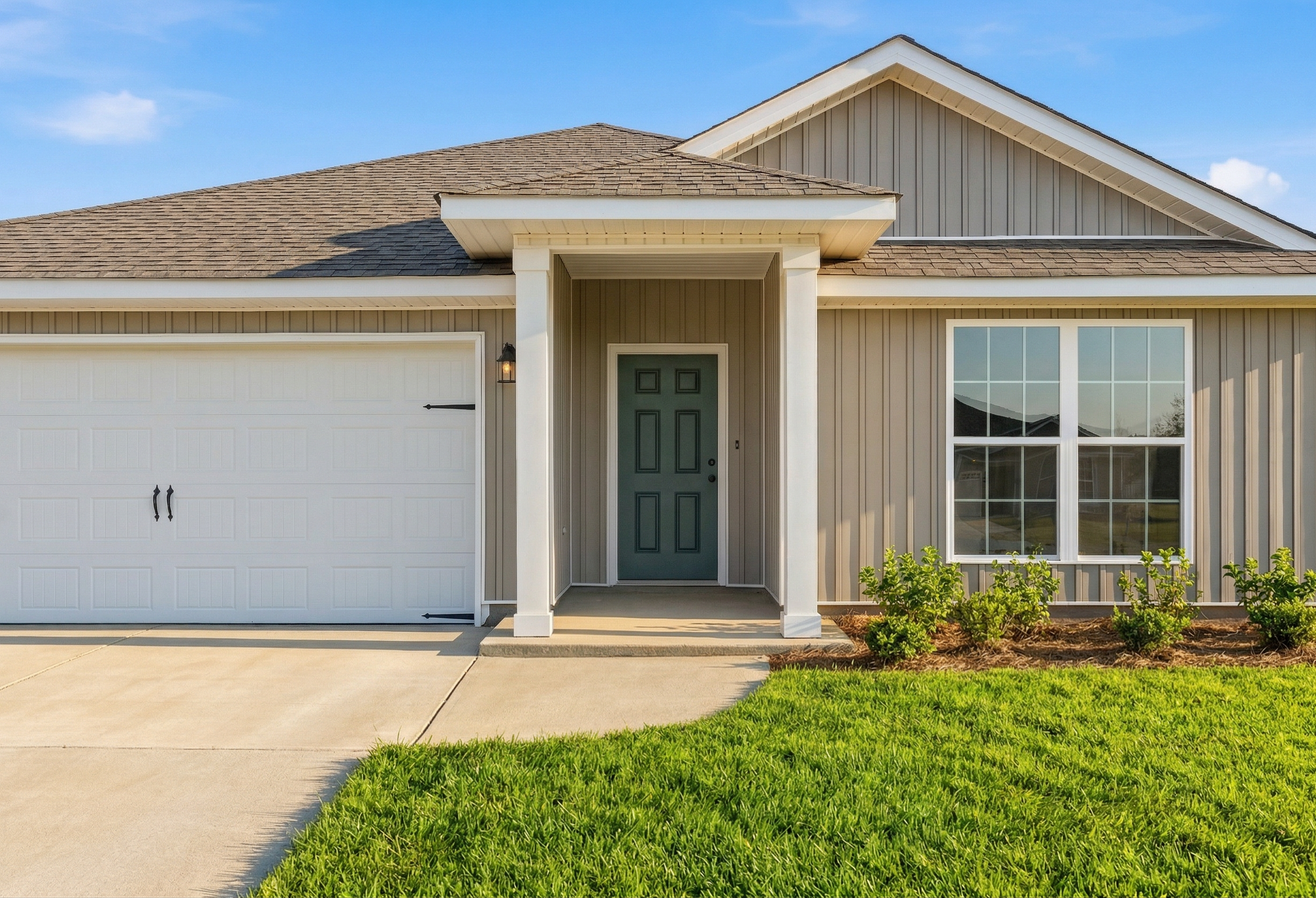 Front elevation of The Daphne V single-story home featuring beige siding, green door, two-car garage, and covered porch in Meridianville AL