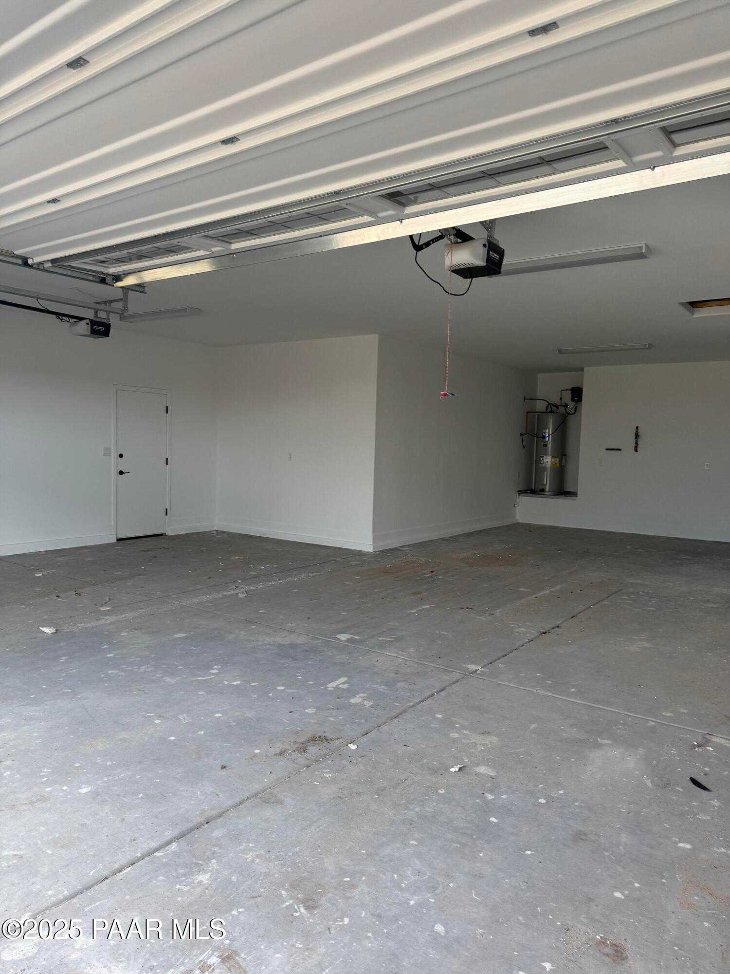 Spacious 4-car garage with open door, concrete floor and water heater in Evermore Homes The Sunrise A, Prescott Valley, Arizona