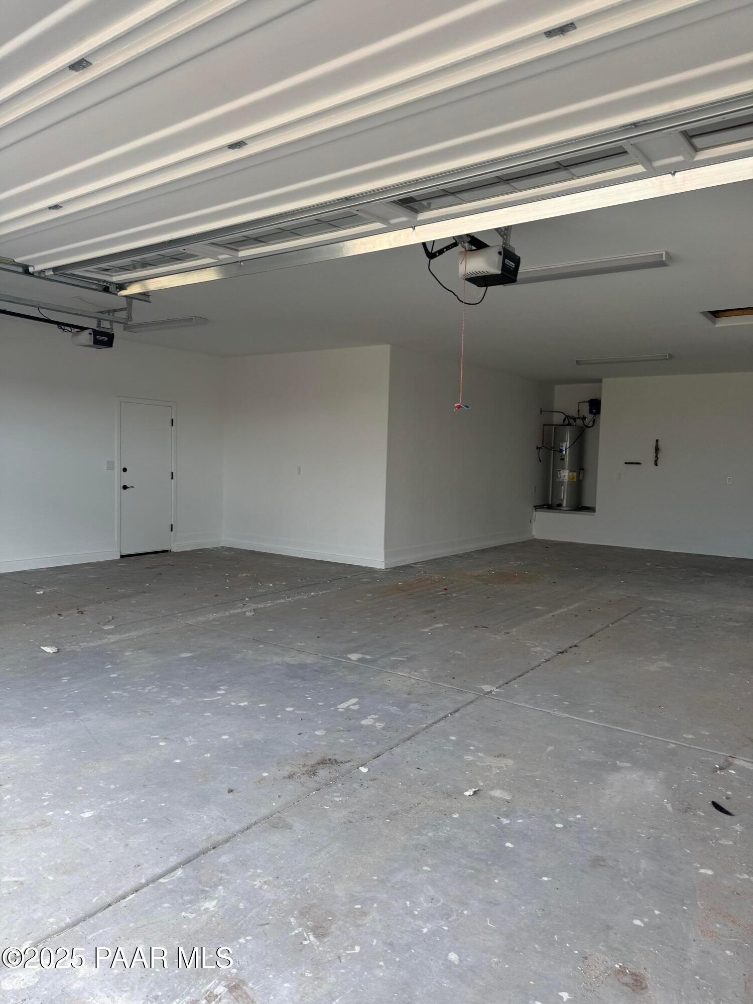 Spacious 4-car garage with open door, concrete floor and water heater in Evermore Homes The Sunrise A, Prescott Valley, Arizona