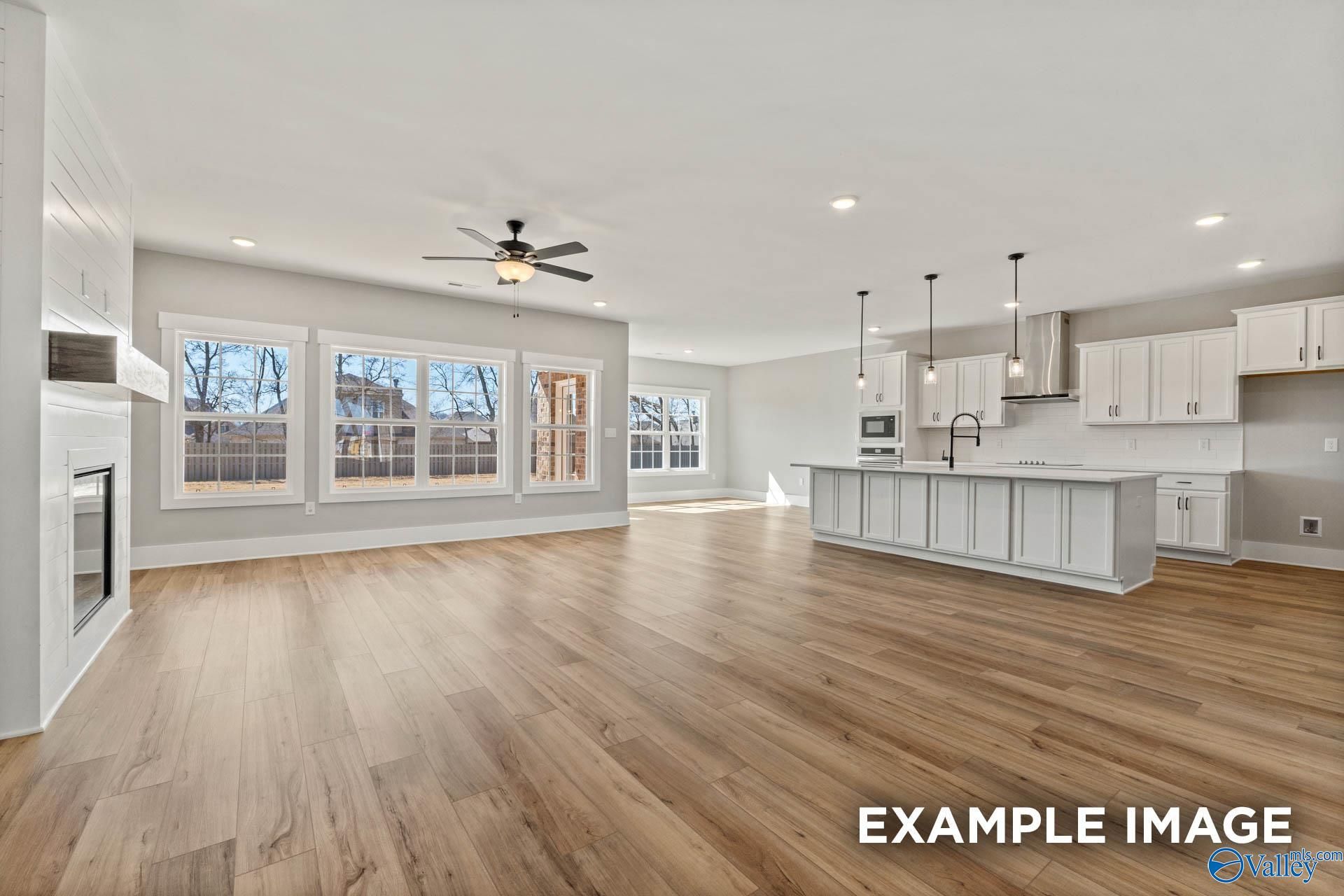 Open-concept living room and kitchen with white cabinetry and fireplace in The Finleigh floor plan, Briercreek, Meridianville.