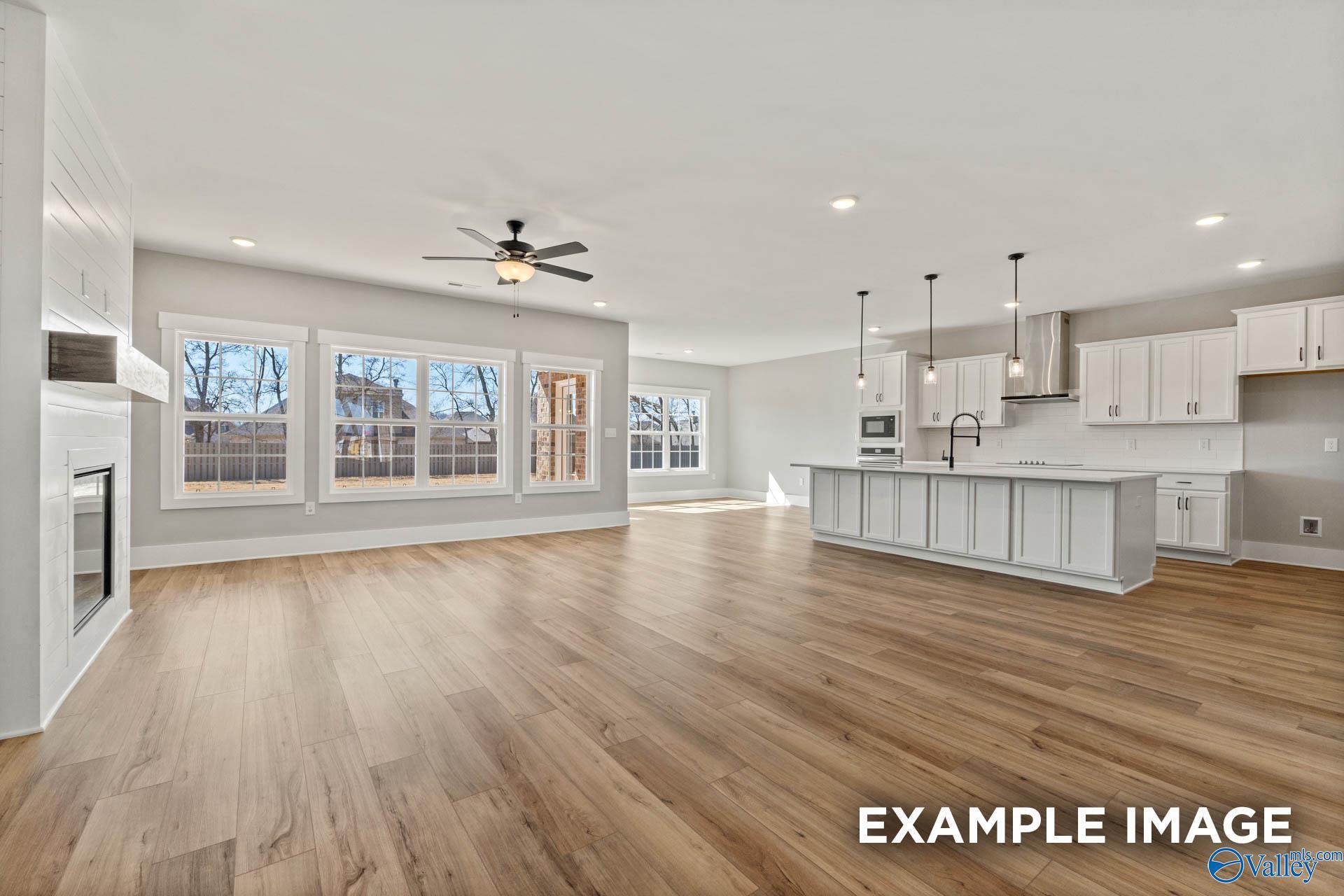 Open-concept living room and kitchen with white cabinetry and fireplace in The Finleigh floor plan, Briercreek, Meridianville.