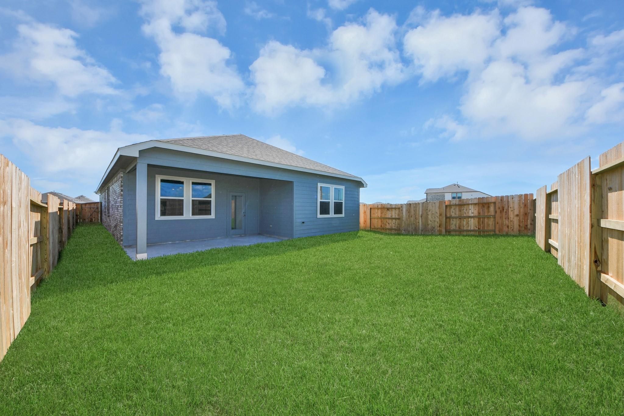 Private backyard with covered patio and blue siding exterior of The Riviera A home in Emberly, Beasley, Texas.