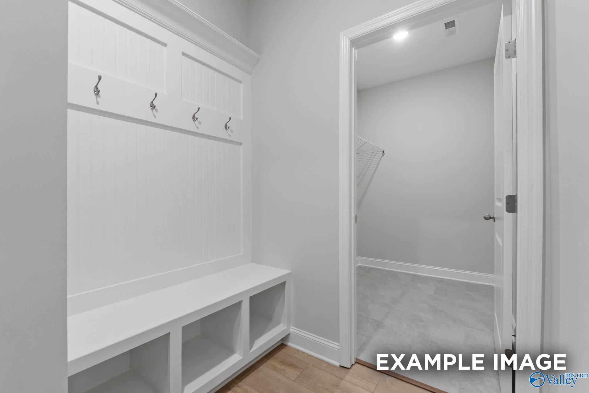White mudroom with built-in bench, coat hooks, and storage cubbies in Davidson Homes The Rockford B, Toney, Alabama