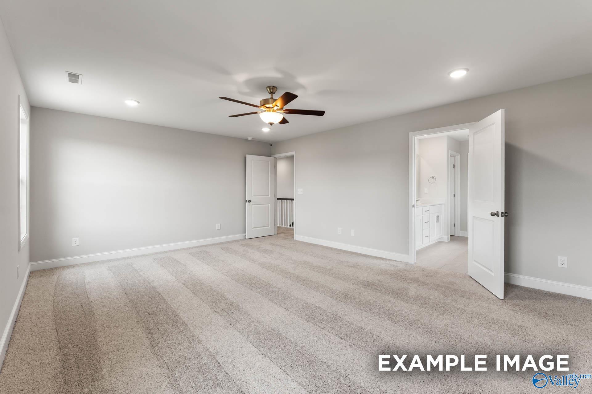 Spacious bedroom with carpet and ceiling fan leading to a private bathroom in The Madison A floor plan, Athens, Alabama.