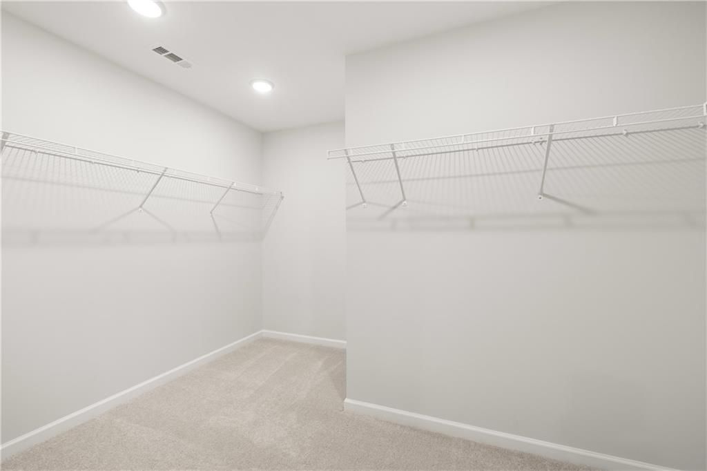 Walk-in closet with wire shelving and carpeted floors in The Sinclair B floor plan at Cedar Farms in Winder, Georgia.