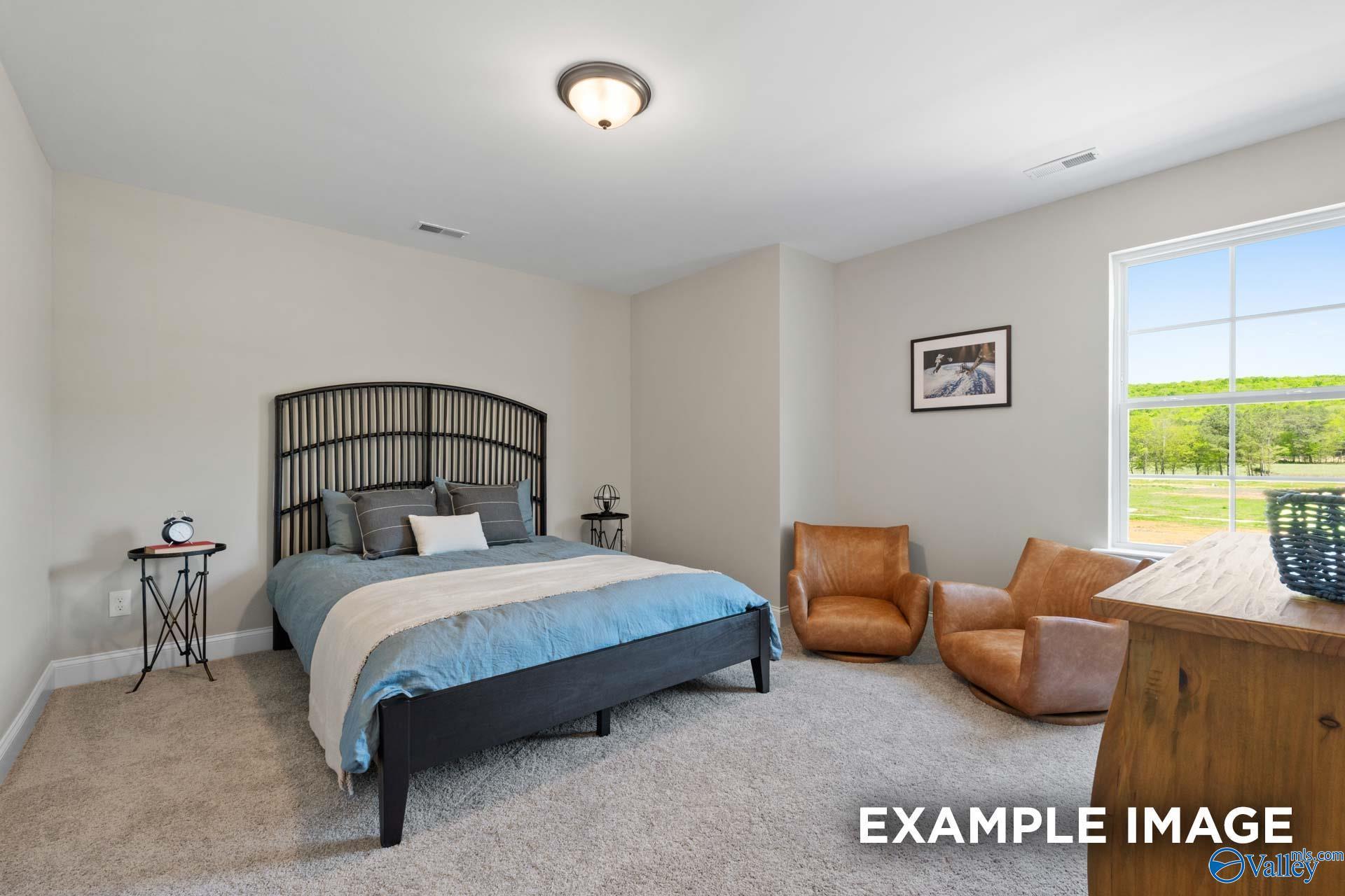 Cozy bedroom with black metal headboard bed, leather chairs, desk, and green field window view in Evermore Homes The Haven E, Owens Cross Roads, AL