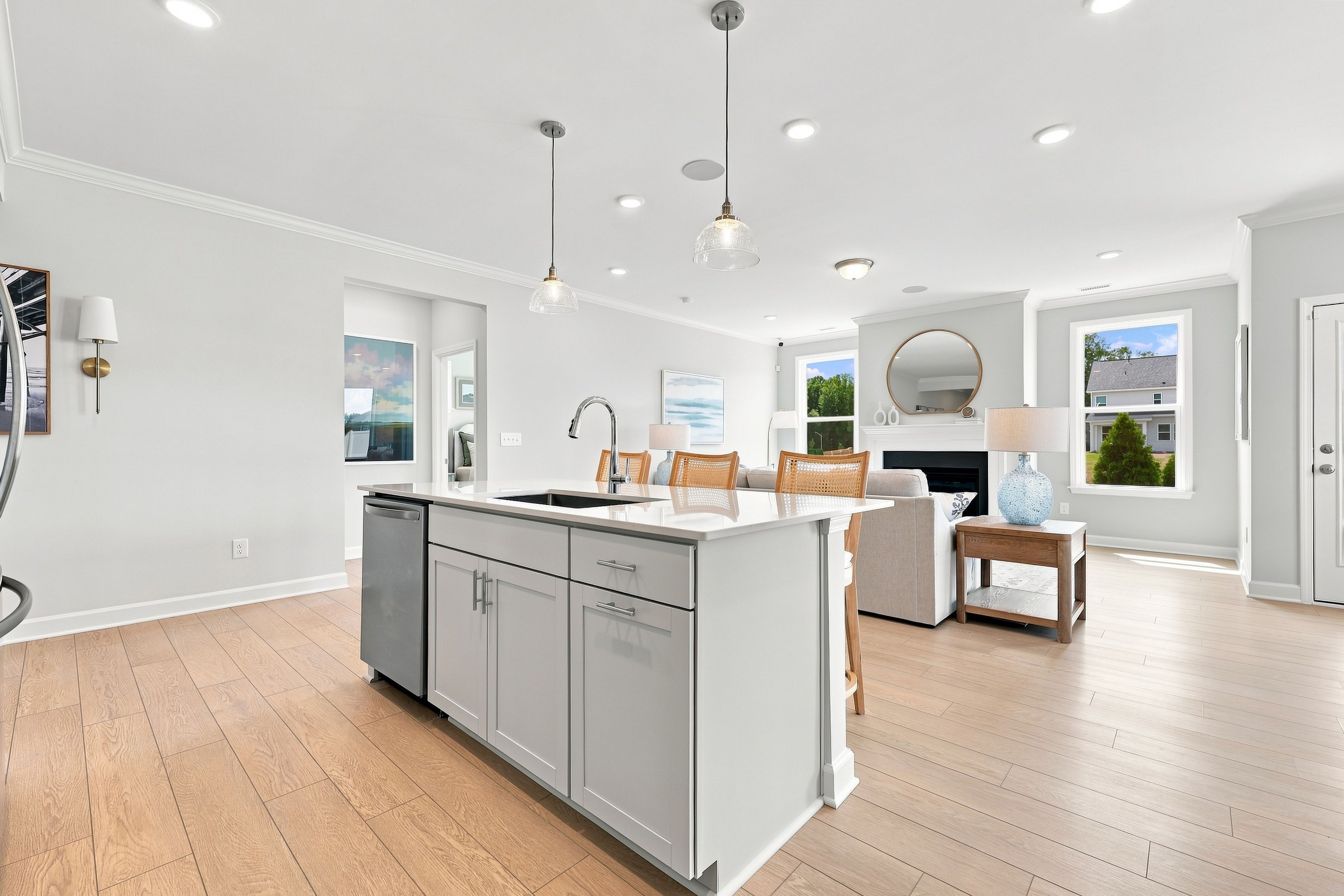 Open-concept kitchen and living area in The Daphne D featuring a large island, modern lighting, and hardwood flooring.