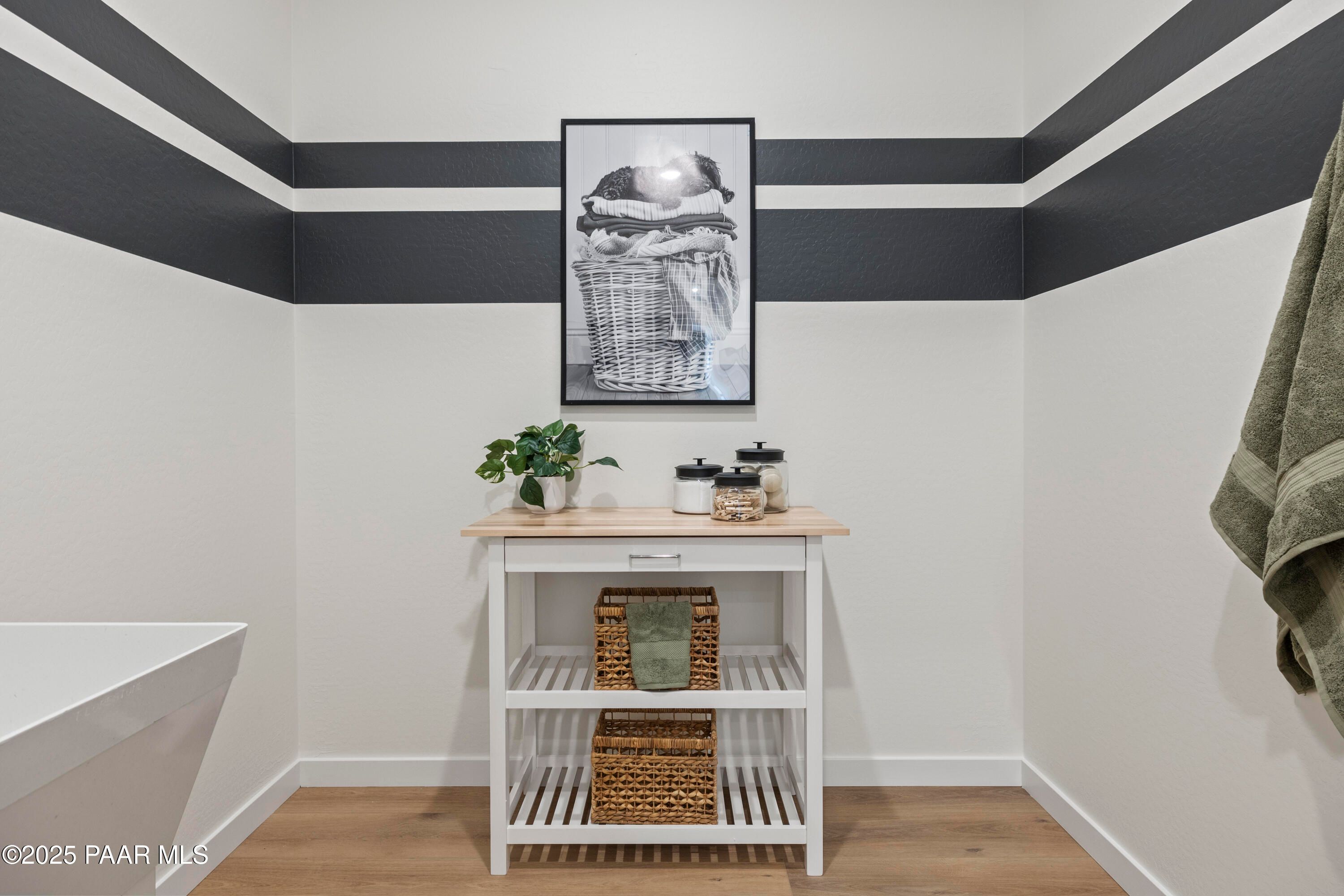 Elegant bathroom with freestanding tub, wooden shelf of rattan baskets, striped walls in Davidson Homes The Blaze D, Prescott AZ
