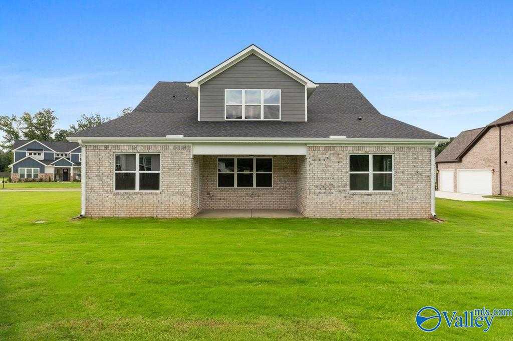 1.5-story brick and siding home with covered front porch, large windows, and green lawn in The Meadows at Hampton Cove, Owens Cross Roads, AL