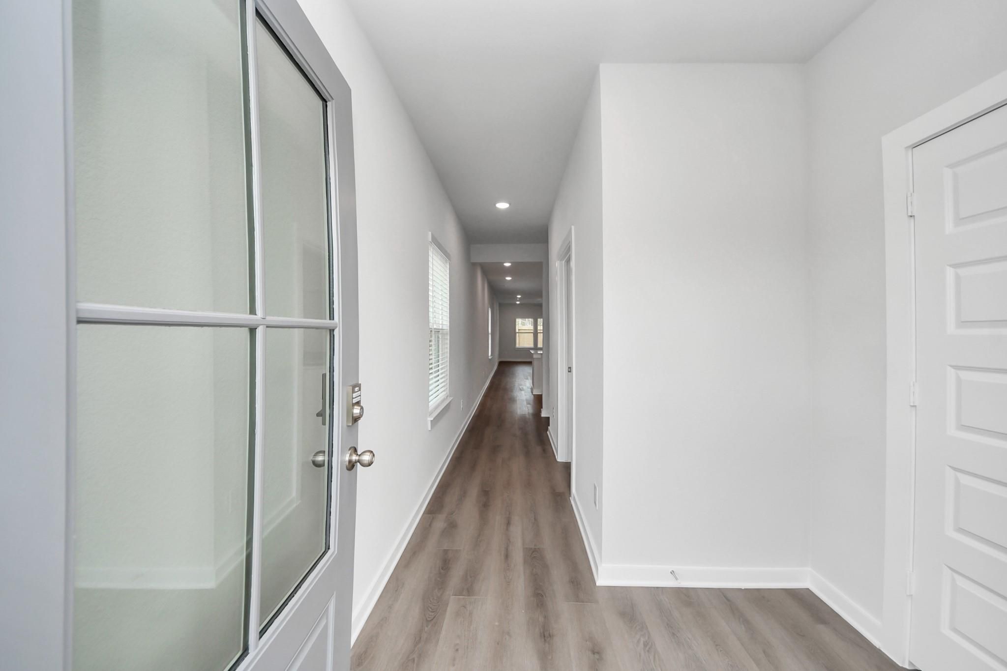 Bright entry foyer with glass-panel front door and wood-look flooring in Davidson Homes Sabine F plan, Caney Creek Place, Conroe TX