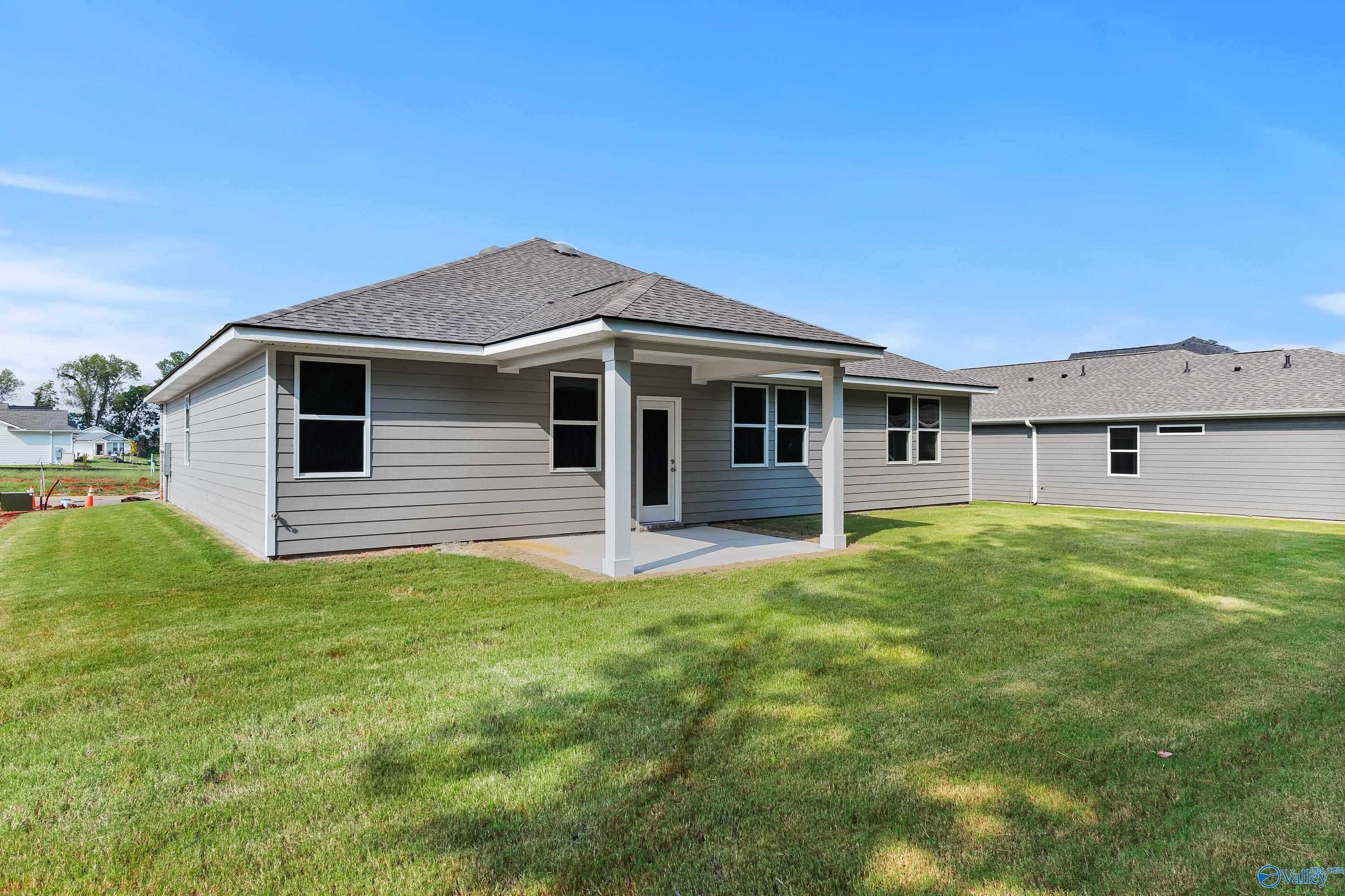 Modern gray one-story home exterior with covered porch, large windows, and green backyard in Evergreen Mill, Madison, Alabama