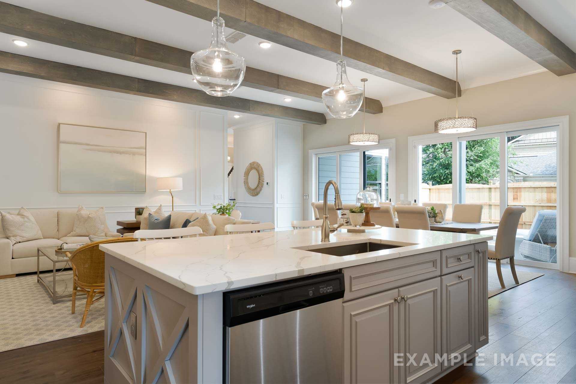 Open-concept kitchen in The Seaside home design with white quartz island, stainless sink, and adjacent living dining area