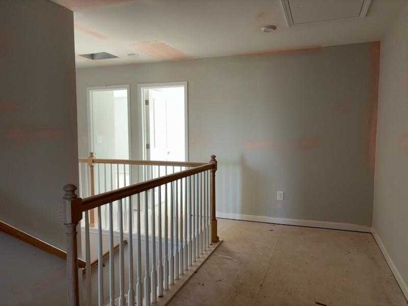 Upstairs landing with wooden staircase, white railings, open doors, and gray walls in The Marion C by Davidson Homes, Winder, Georgia
