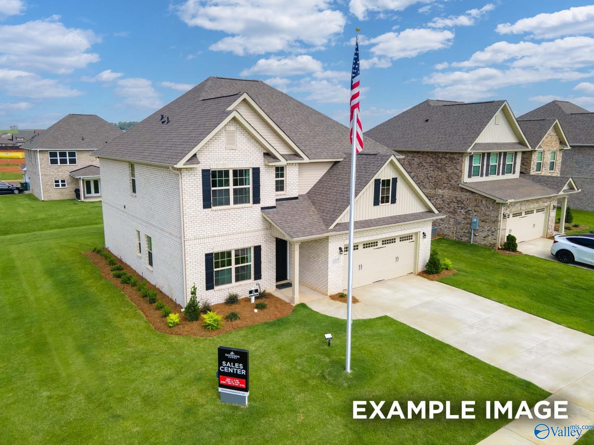 Two-story white brick home with black shutters, American flag, and landscaped yard in Davidson Homes' Ivy Hills community, Toney, Alabama