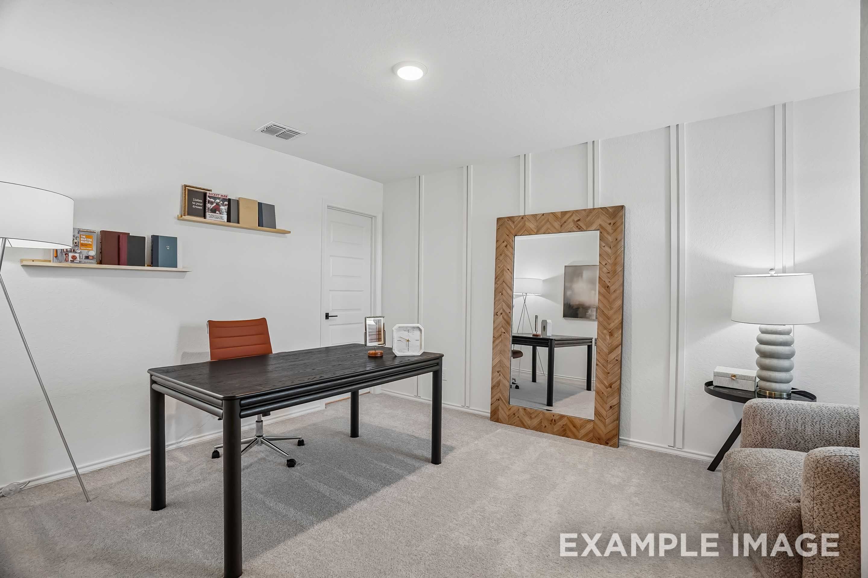 Modern home office in The Pinecrest D floor plan featuring a black desk, floor mirror, and board and batten accent wall.