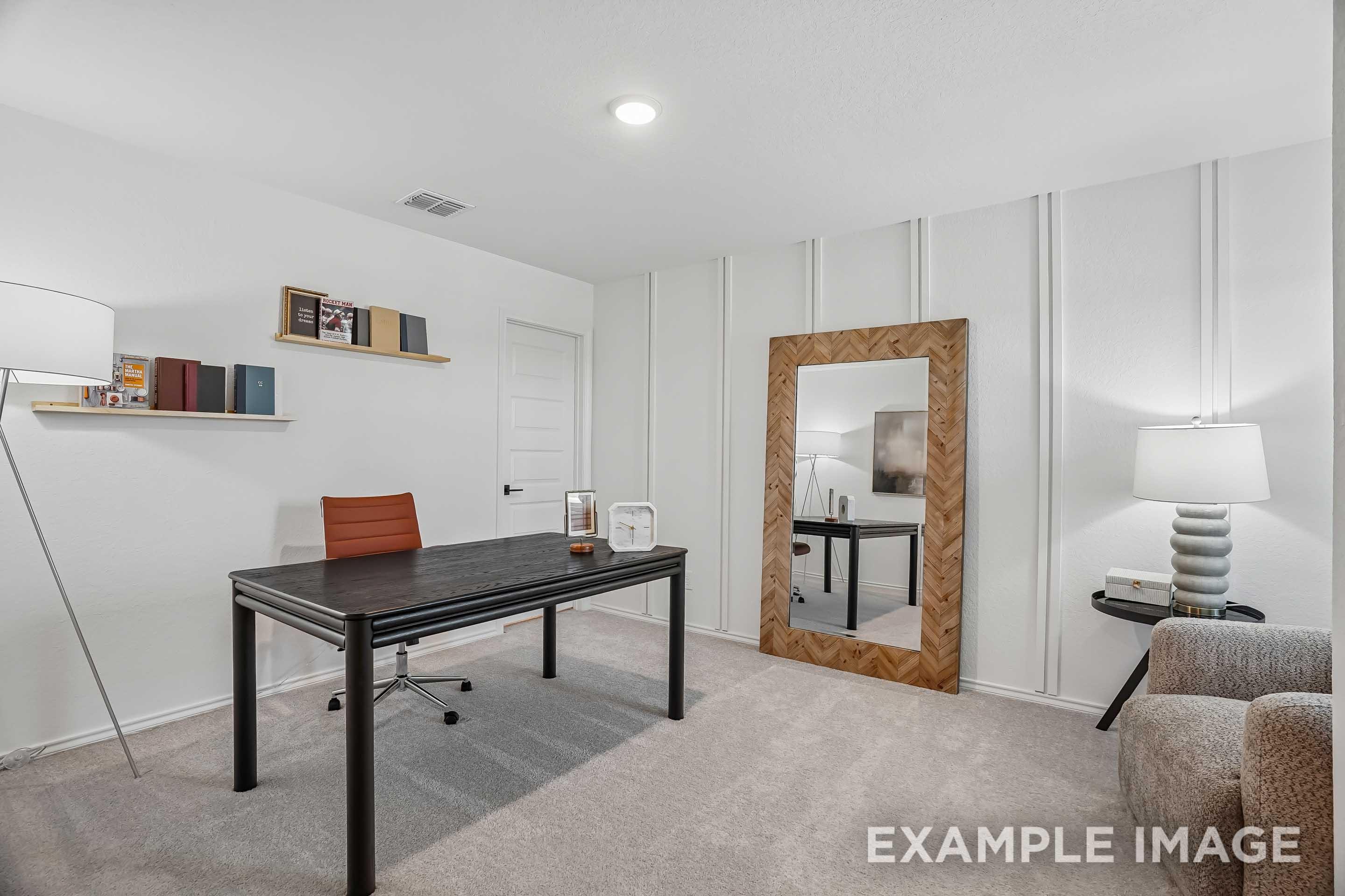 Modern home office in The Pinecrest D floor plan featuring a black desk, floor mirror, and board and batten accent wall.