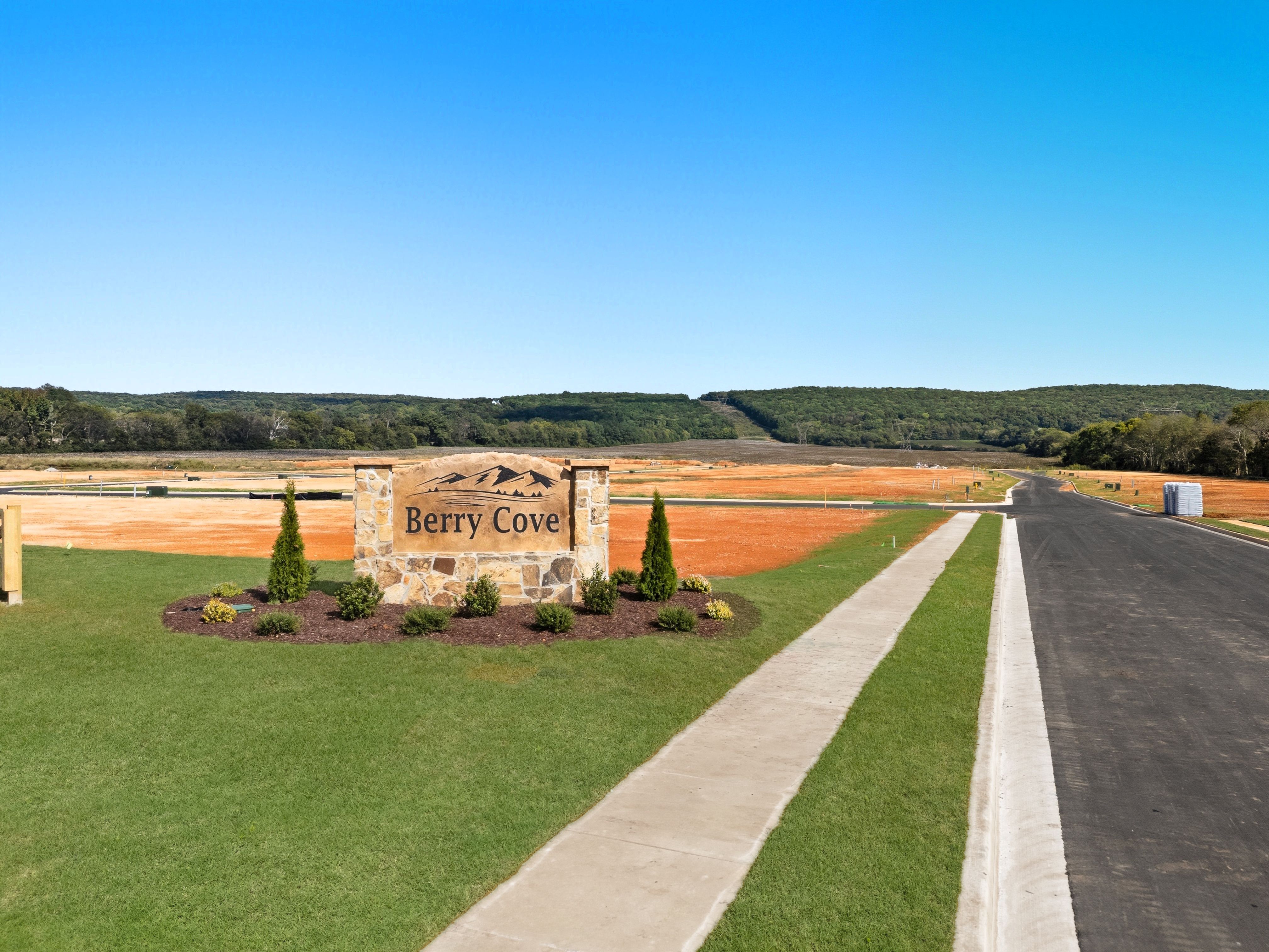 Berry Cove entrance sign in New Market Alabama with stone pillar landscaped shrubs evergreens and paved road