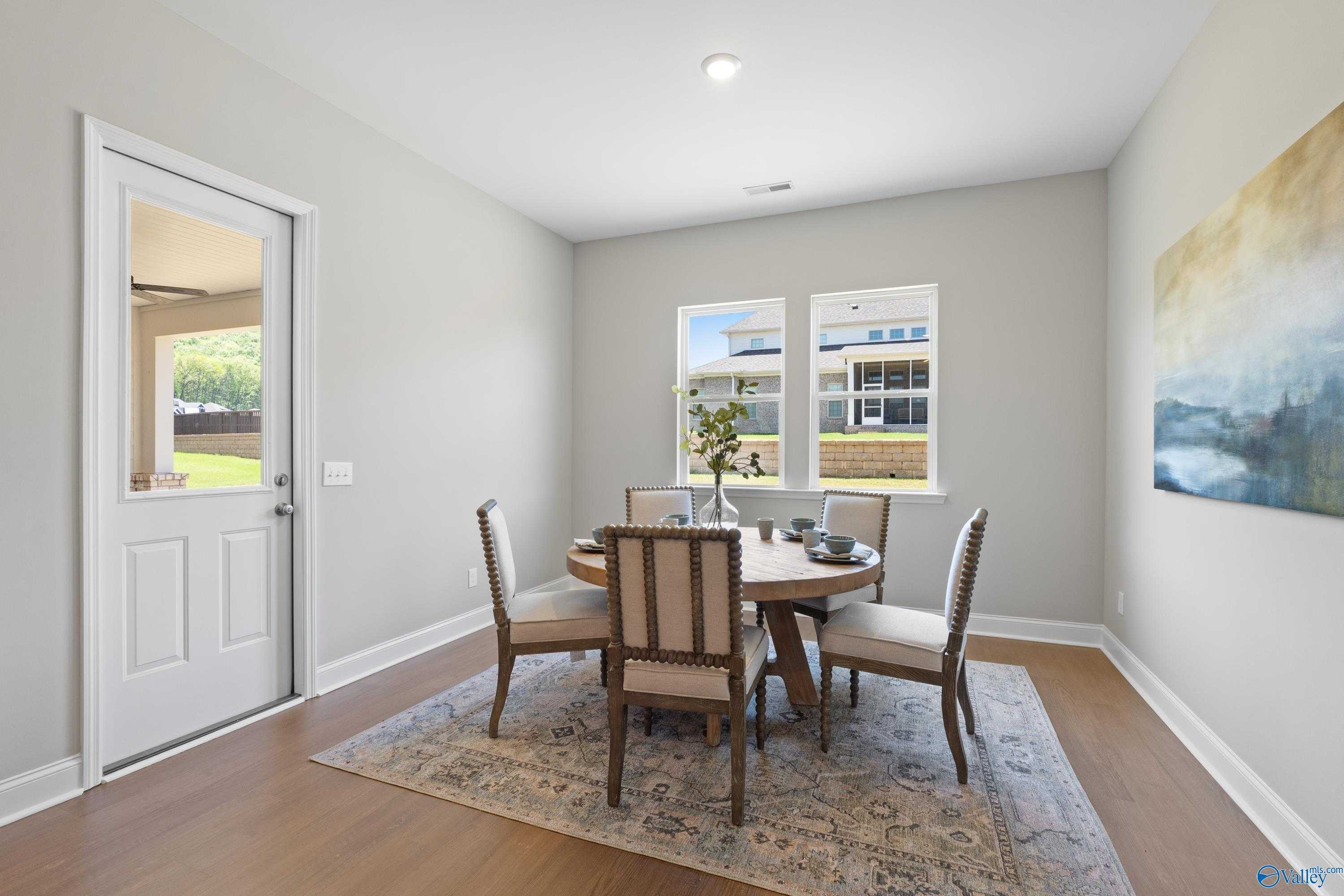 Elegant dining room featuring oval wood table, upholstered chairs, and abstract art in Evermore Homes The Haven, Owens Cross Roads, Alabama