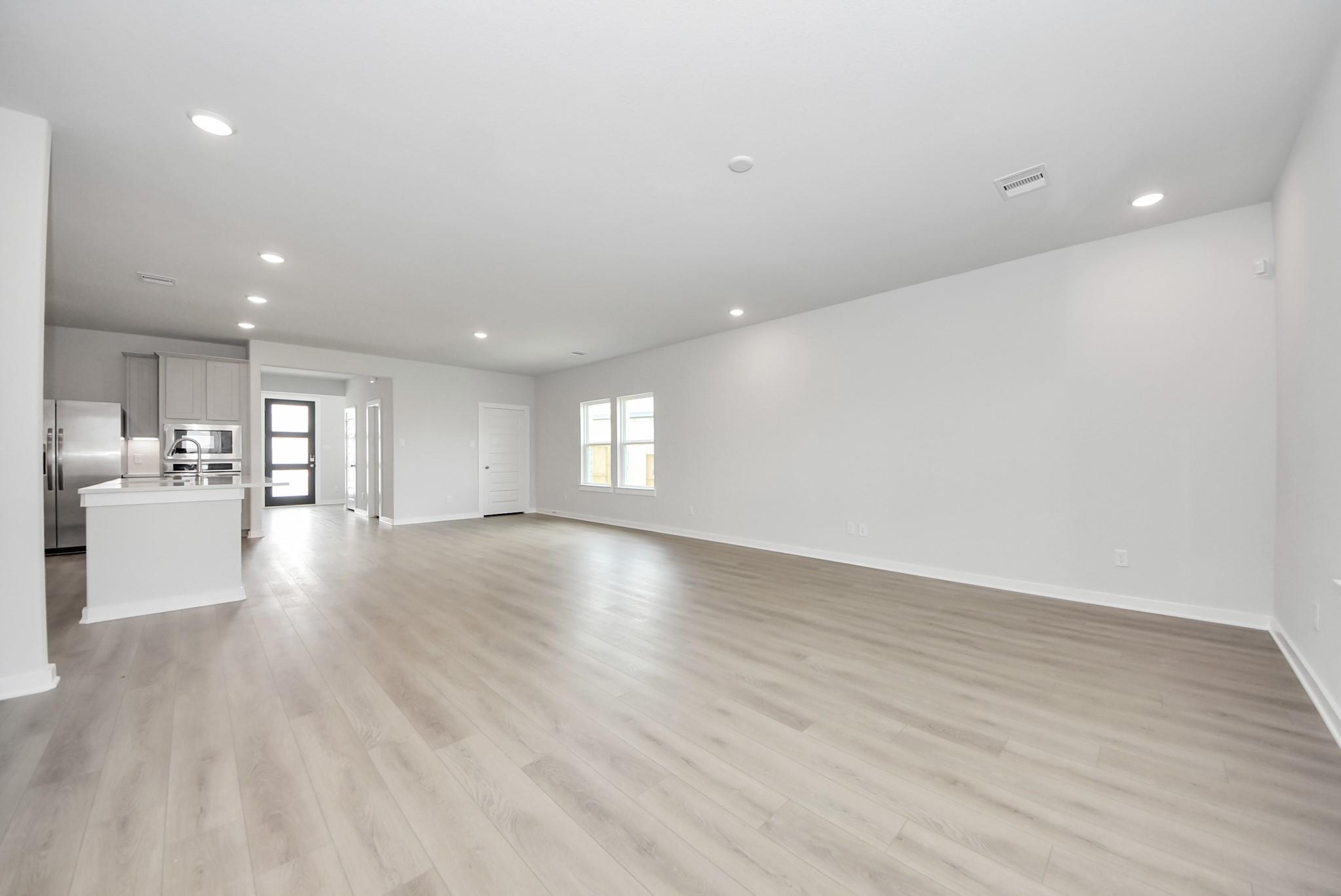 Spacious open-concept living area with light wood flooring in The Verano B floor plan by Davidson Homes in Sunterra, Katy.