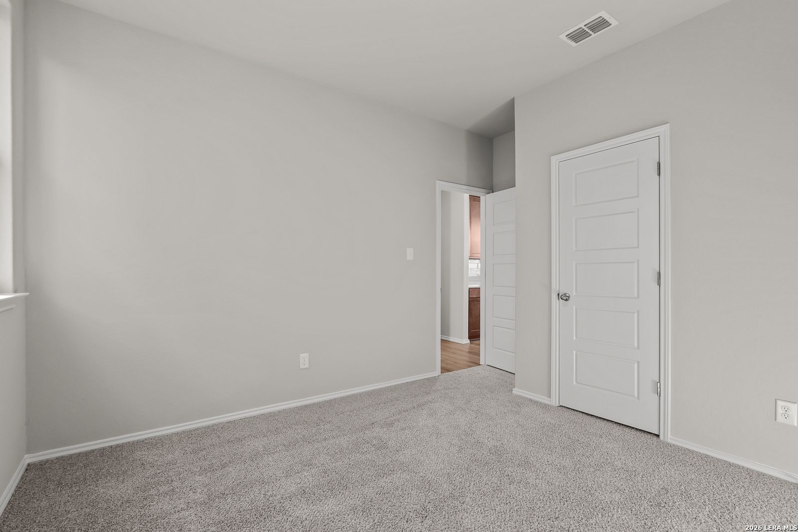 Spacious secondary bedroom with light gray walls, beige carpet, and adjacent bath in Davidson Homes The Frio B, San Antonio
