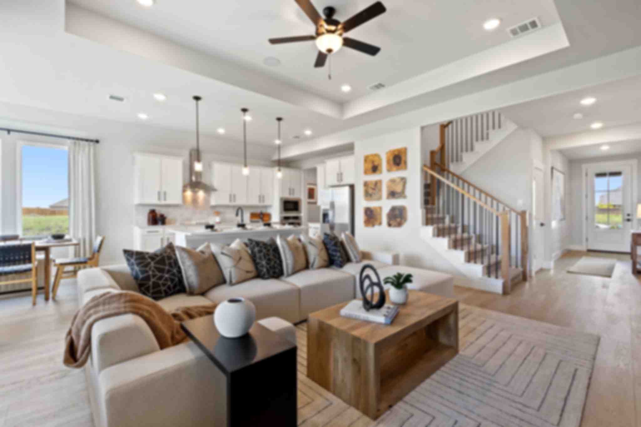 Modern white kitchen with large island, bar stools, pendant lights, and large windows at Parks at Foster Crossing, Anna TX