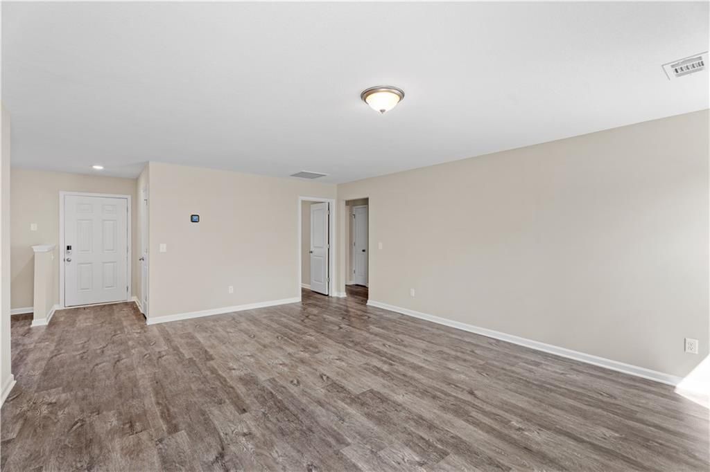 Spacious entry hallway with light wood floors, beige walls, and white doors in Davidson Homes The Washington, Phenix City AL